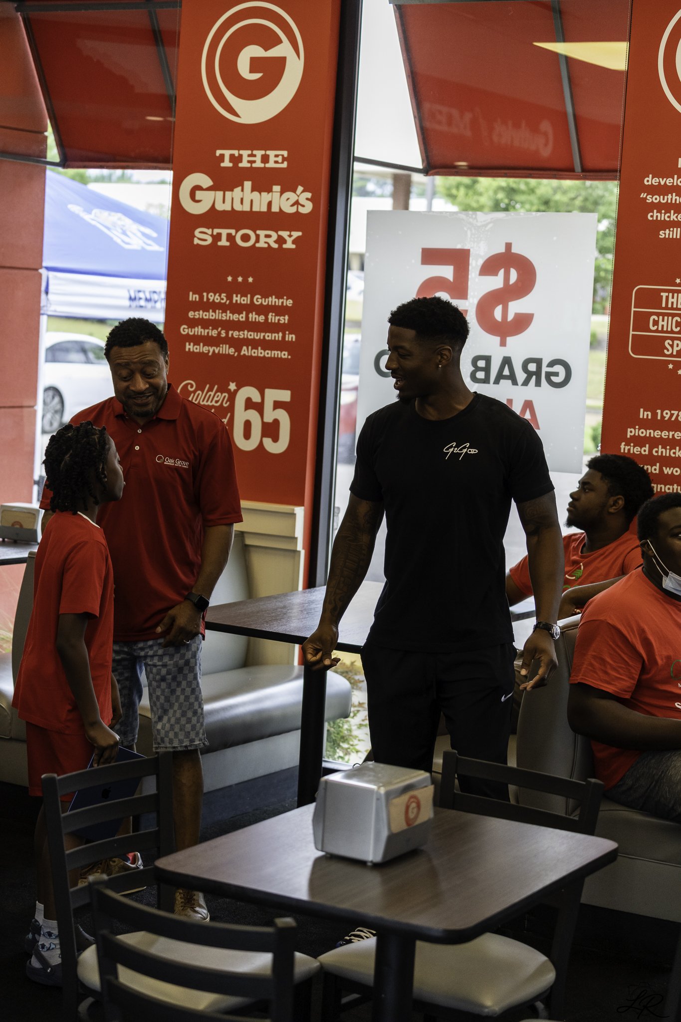 People chatting inside a fast food restaurant, with red and blue signs displaying the restaurant's history.