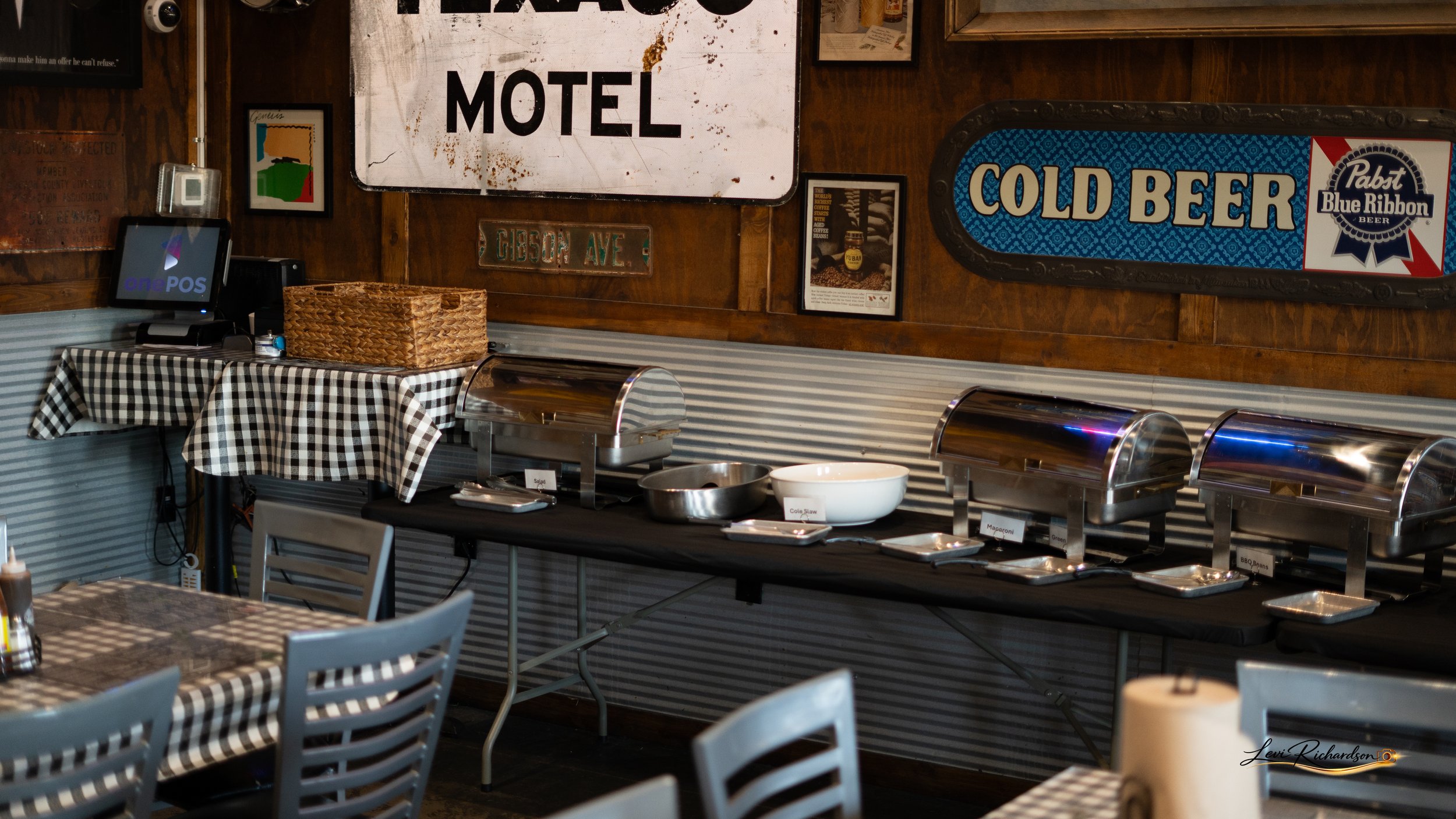 Buffet table set with chafing dishes in a restaurant with vintage signs and wooden paneling.