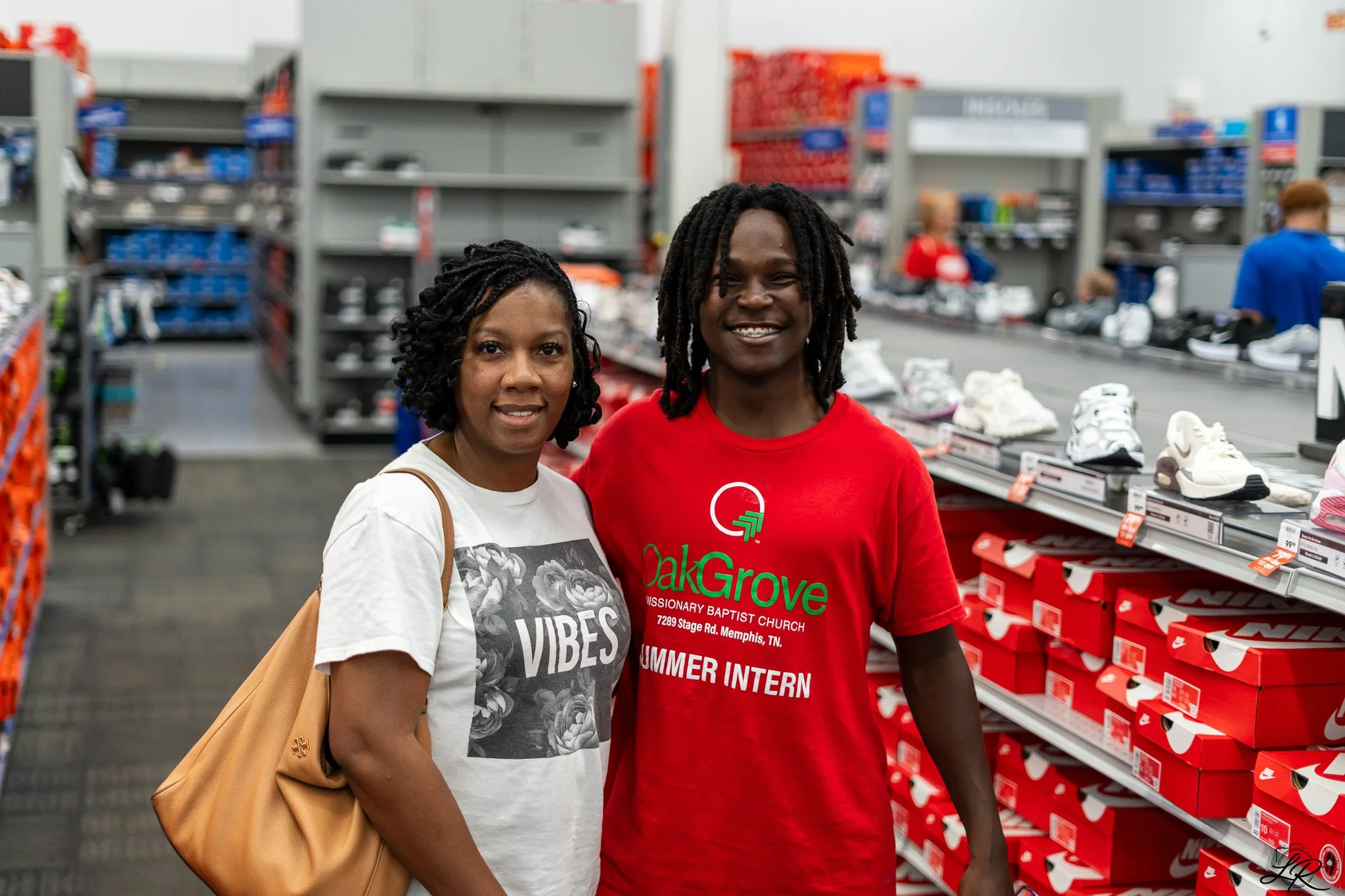 Two women standing inside a retail store, surrounded by shoe shelves and other shoppers.