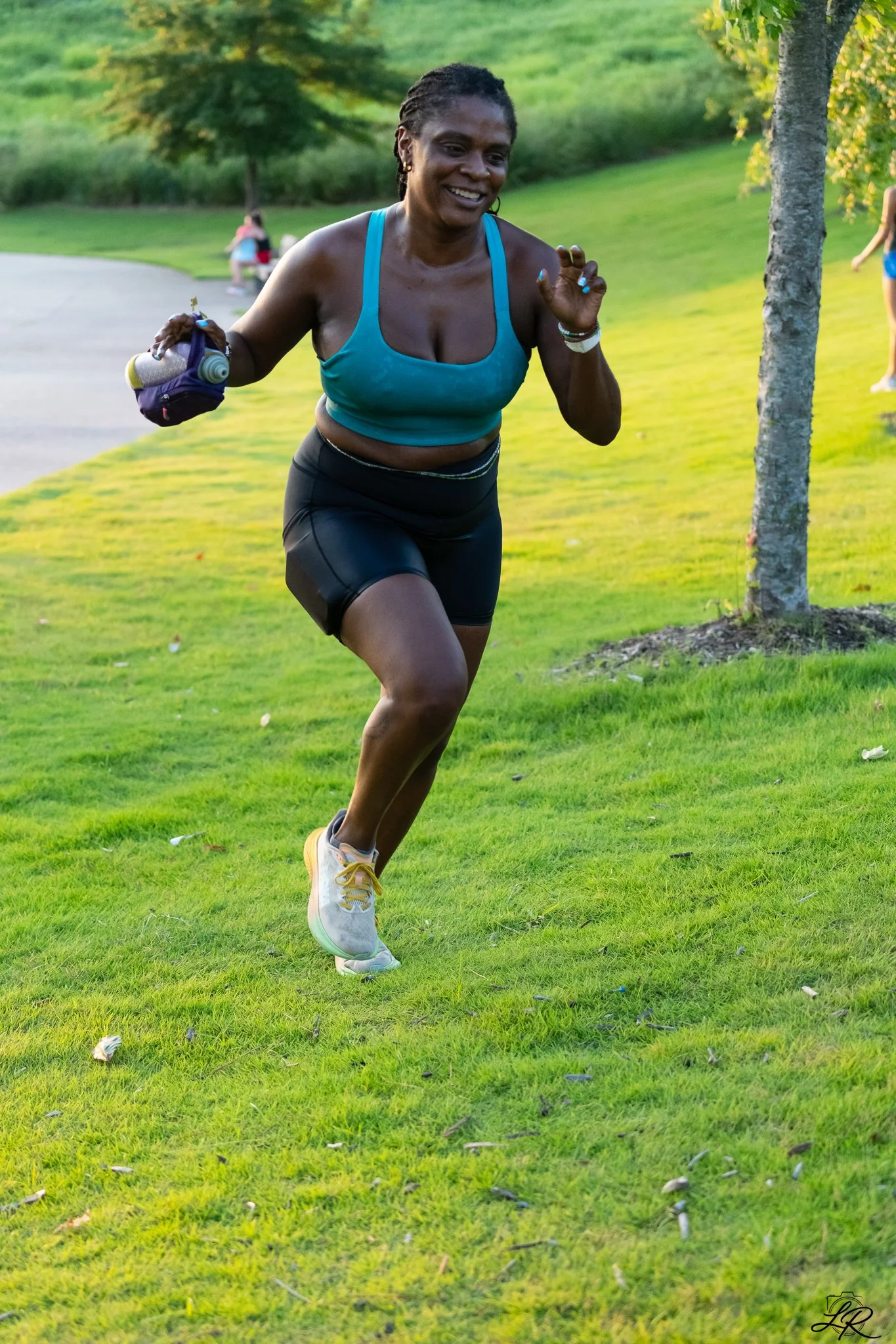 Woman running outdoors on a grassy park area with trees.