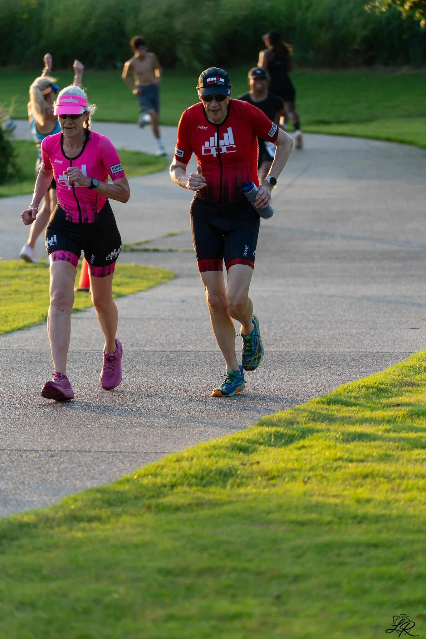People running outdoors on a paved path during daytime.