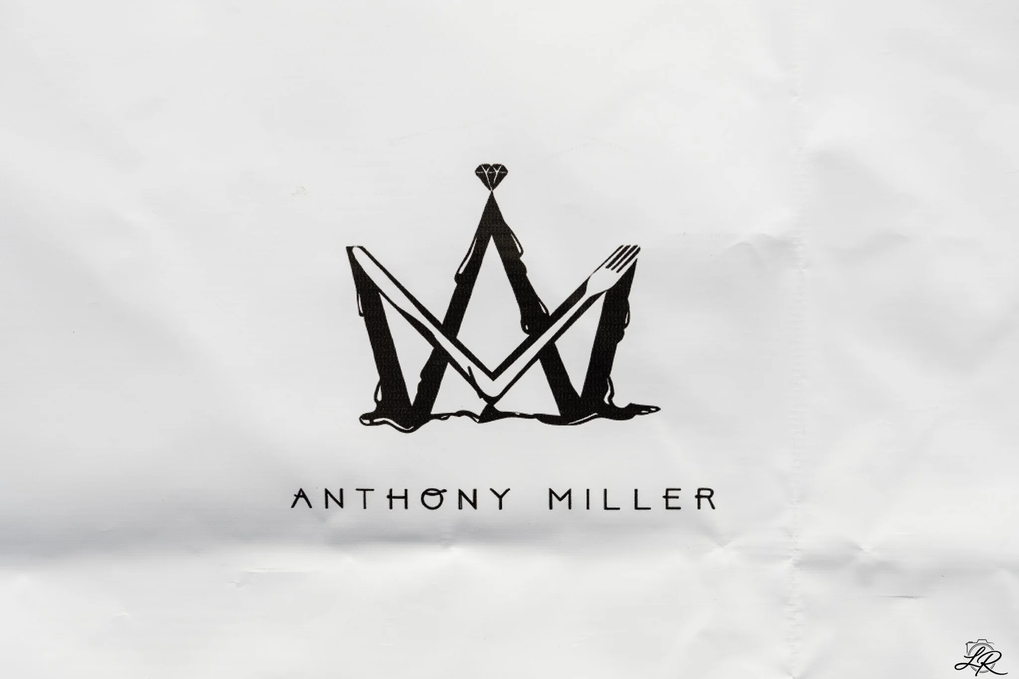 Book cover with a black abstract line drawing of a figure sitting cross-legged, holding a diamond shape above the head, and the title "The Anthony Miller" below the drawing.