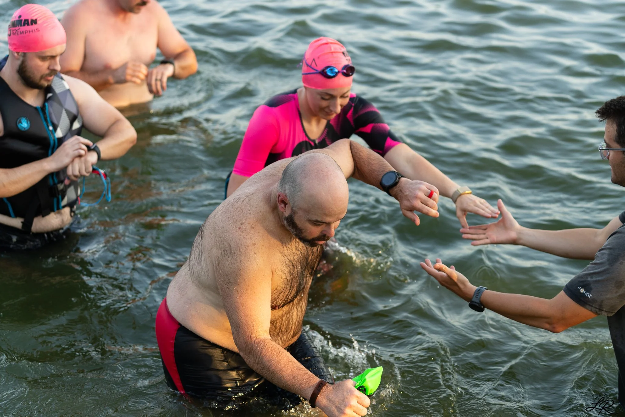 A group of people are standing in water during a baptism ceremony, with one man being baptized and others supporting him.