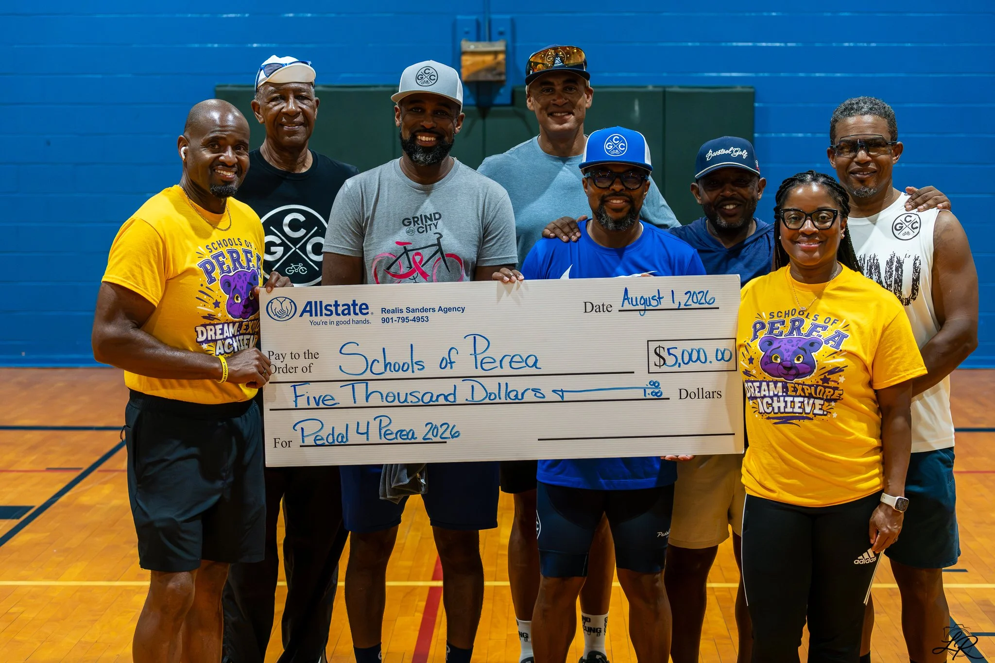Group of people holding a large check for $5,000 at an indoor sports court