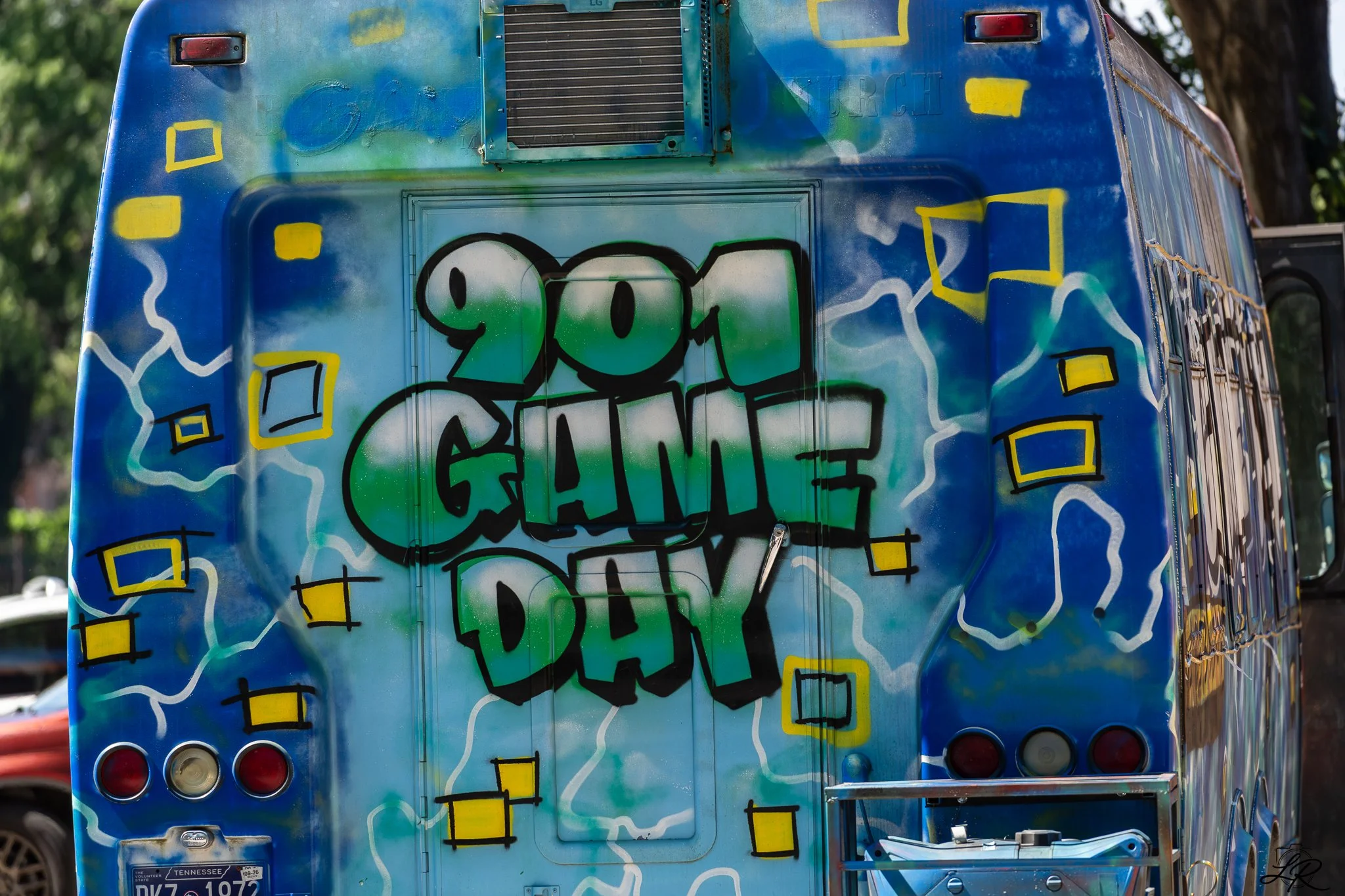 Graffiti art on the back of a blue food truck featuring colorful shapes and the words 'YOU CAN'.