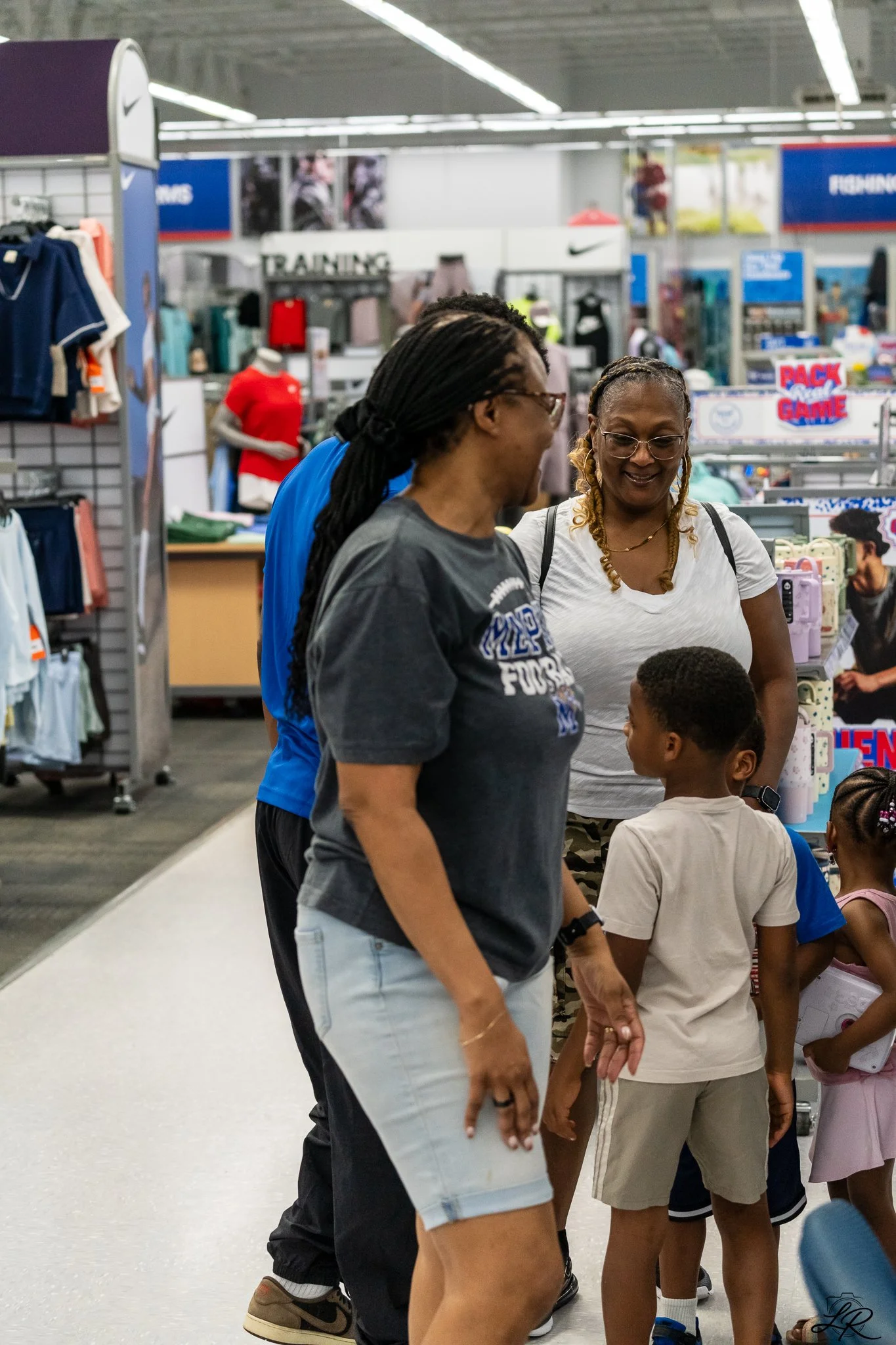People shopping at a sporting goods store, with clothing and sports equipment on display.