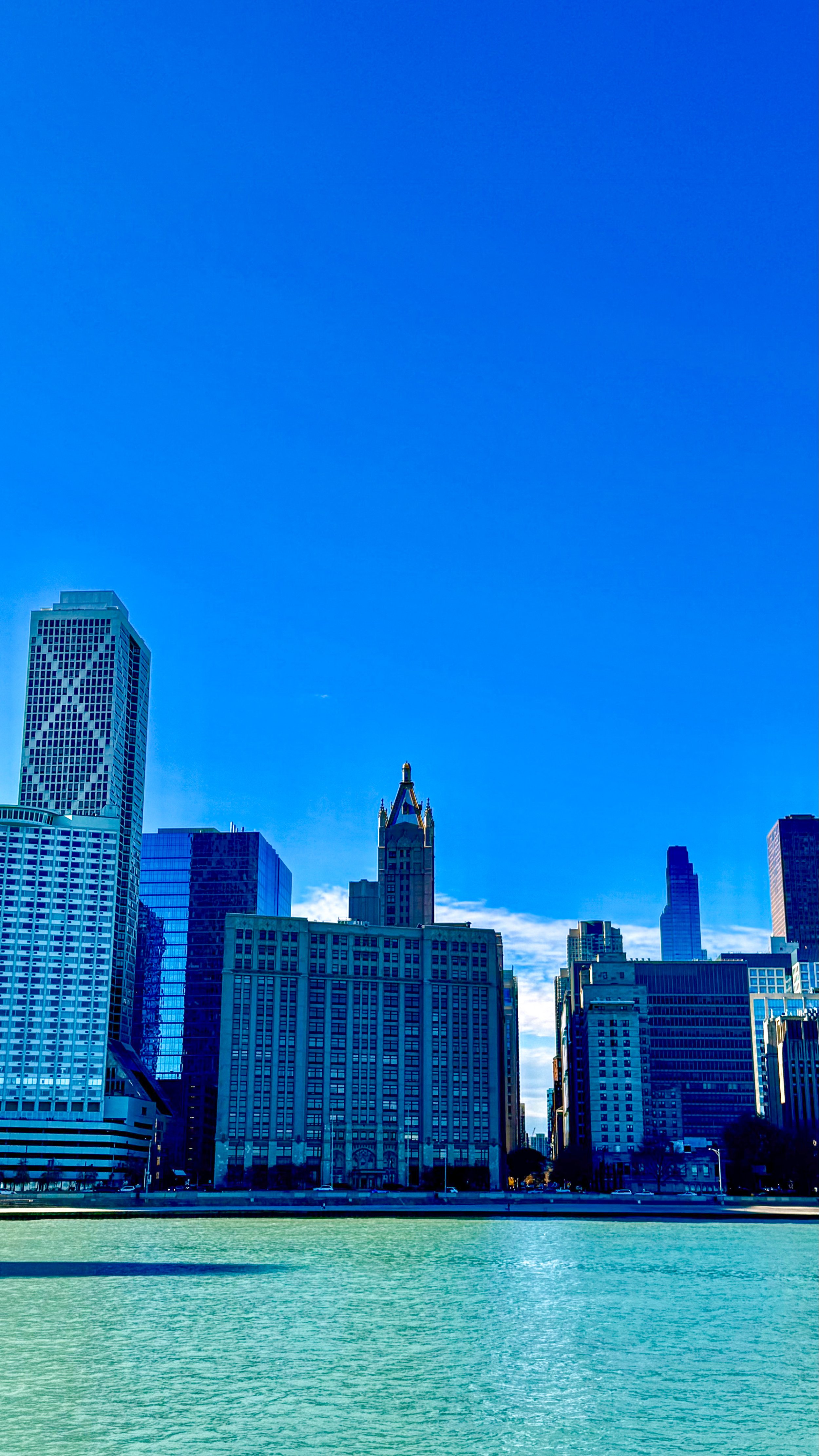 Skyscrapers and buildings along a waterfront on a sunny day with a clear blue sky.