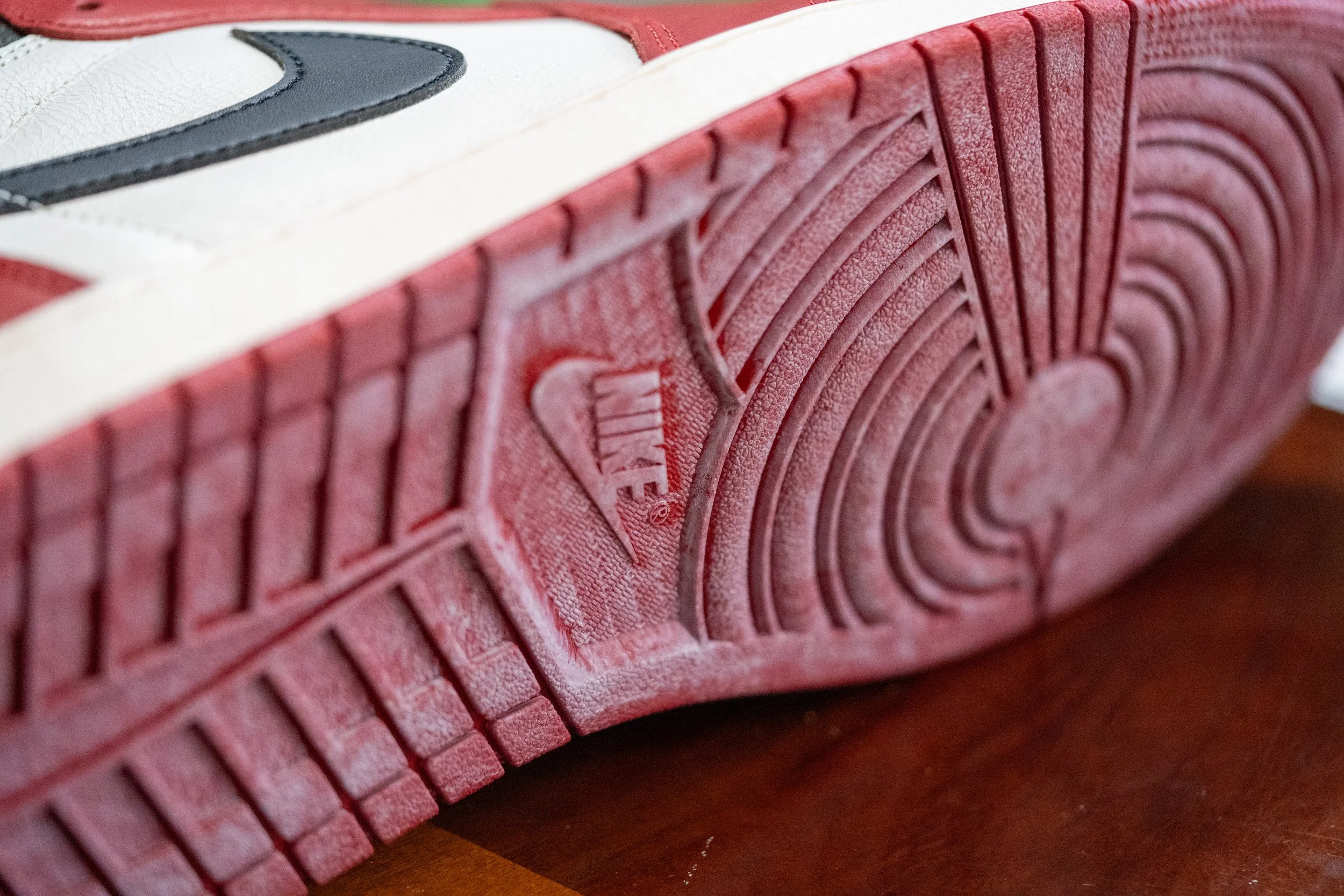 Close-up of the sole of a white and red Nike sneaker showing the detailed tread pattern.