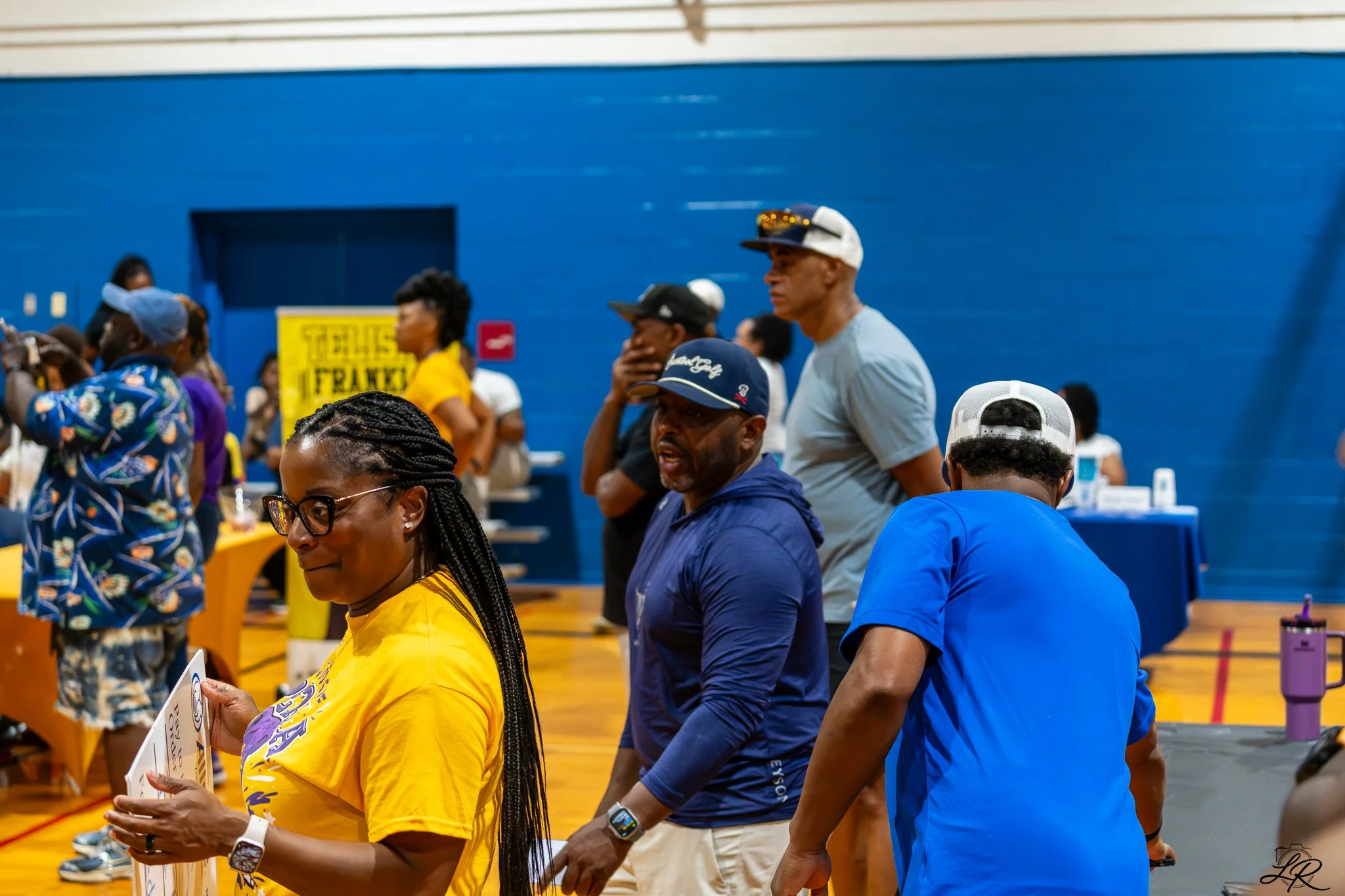 People standing in line at an indoor event with a blue wall in the background.