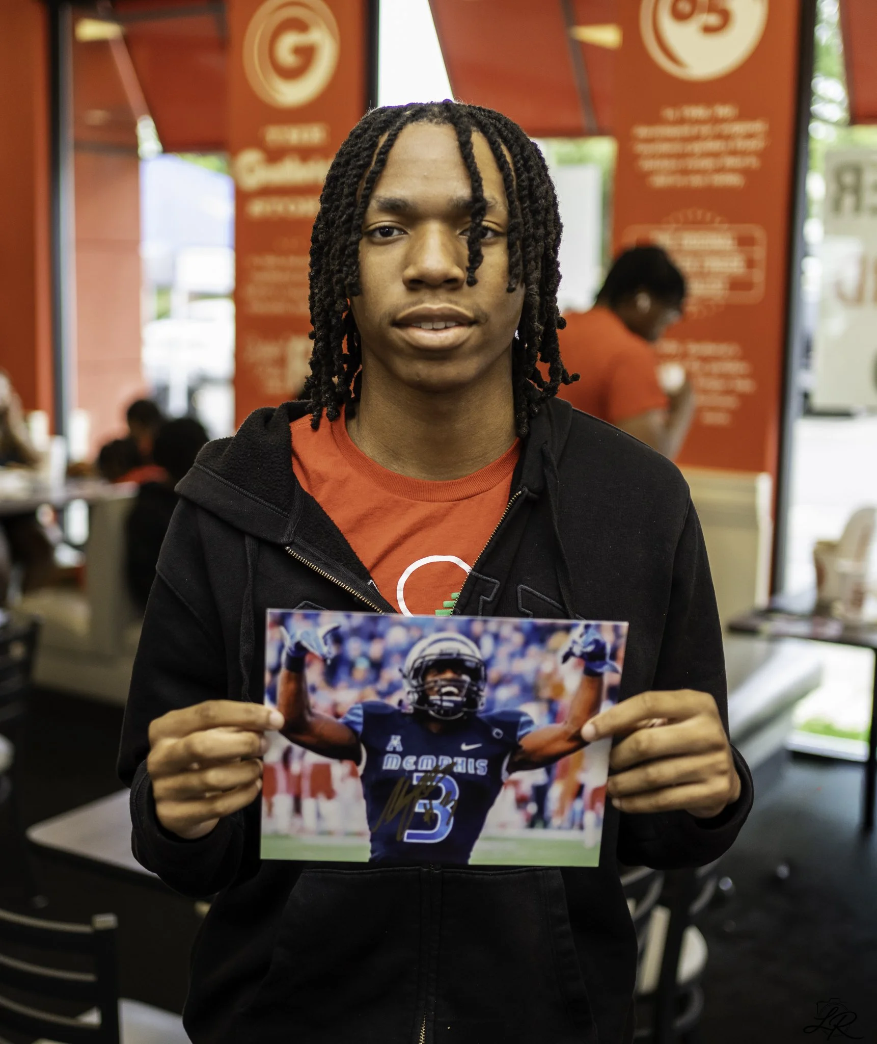 Person at a Memphis football game holding a photo of a football player in a helmet and jersey.