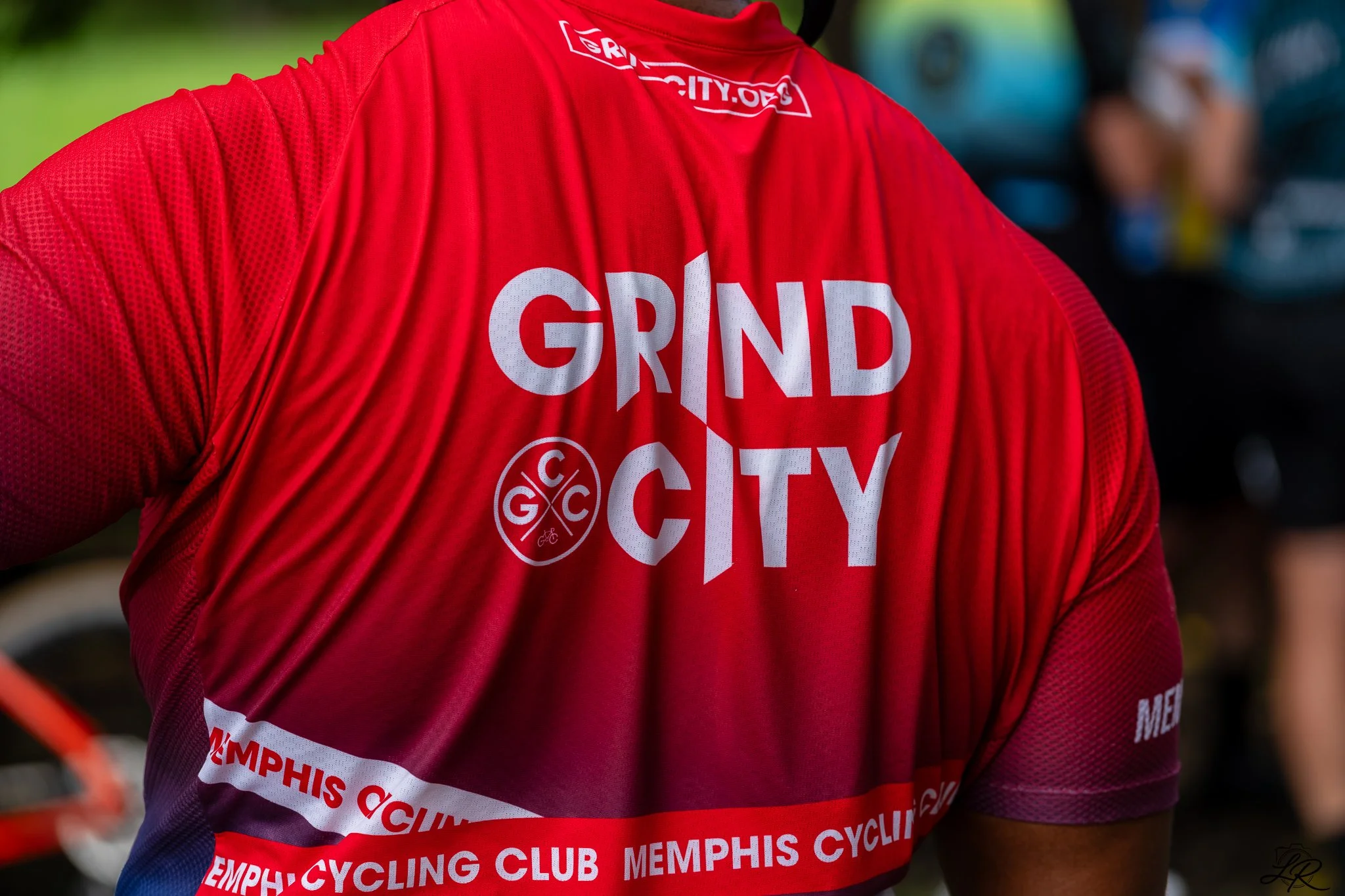 Person wearing a red cycling jersey with the words 'Grand City' and 'Memphis Cycling Club' printed on it. The jersey has a logo and various other text.