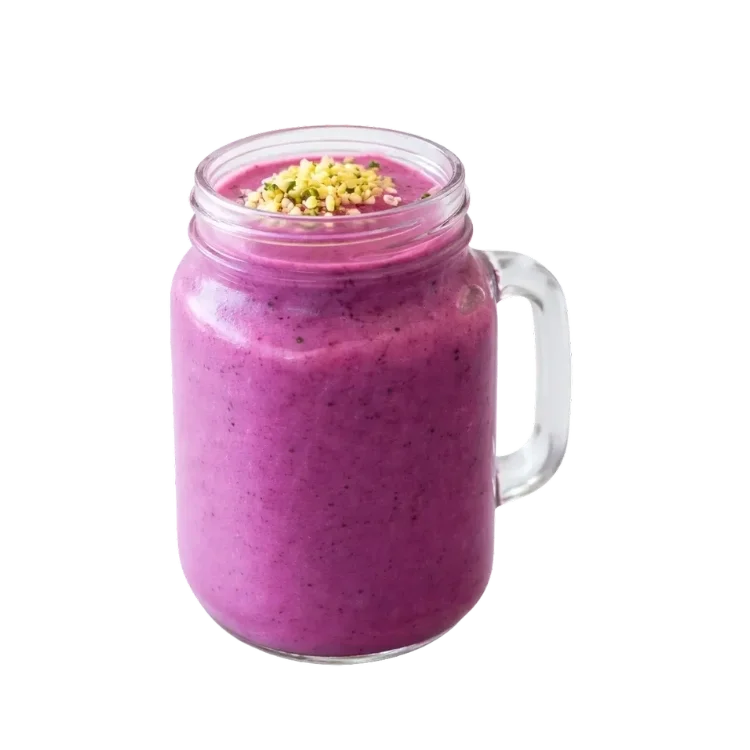 A vibrant pink smoothie in a glass mason jar with a handle, topped with chopped pistachios.
