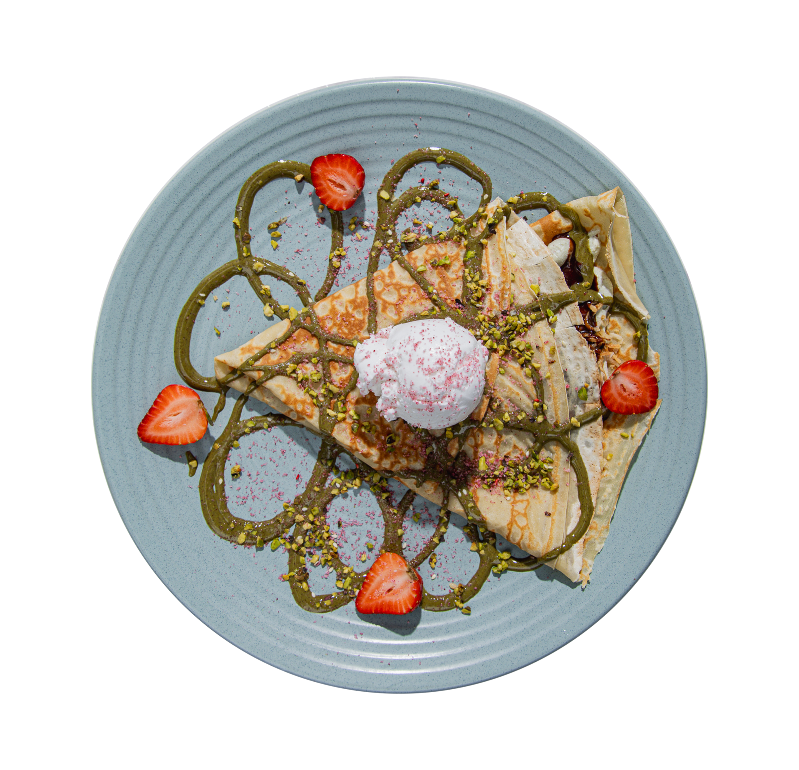 Plate of crepes topped with strawberry slices, whipped cream, chopped pistachios, chocolate drizzle, and green sauce, garnished with pink powder.