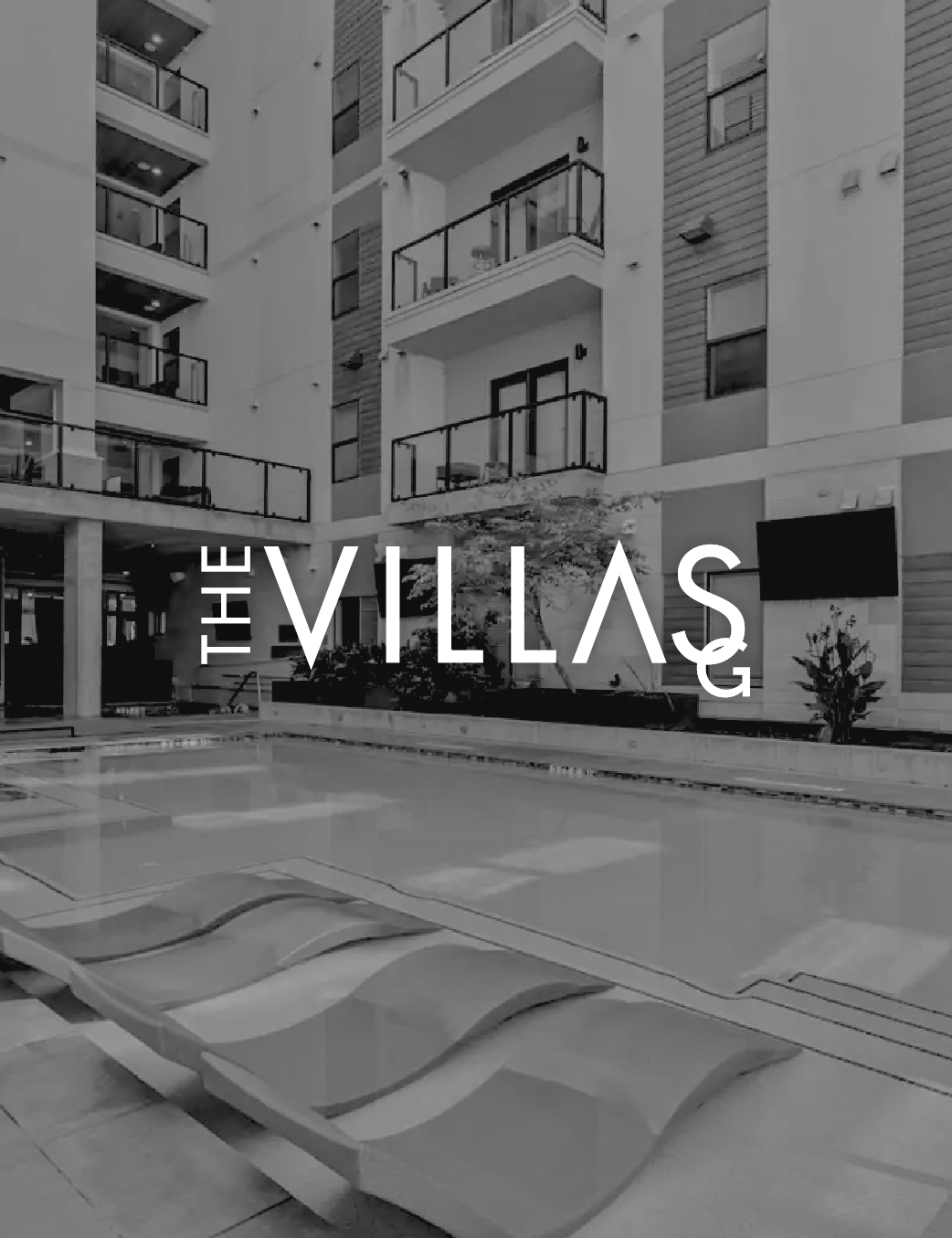 An outdoor swimming pool area in an apartment complex named The Villas, with multi-story residential buildings, balconies, and a modern aesthetic in grayscale.