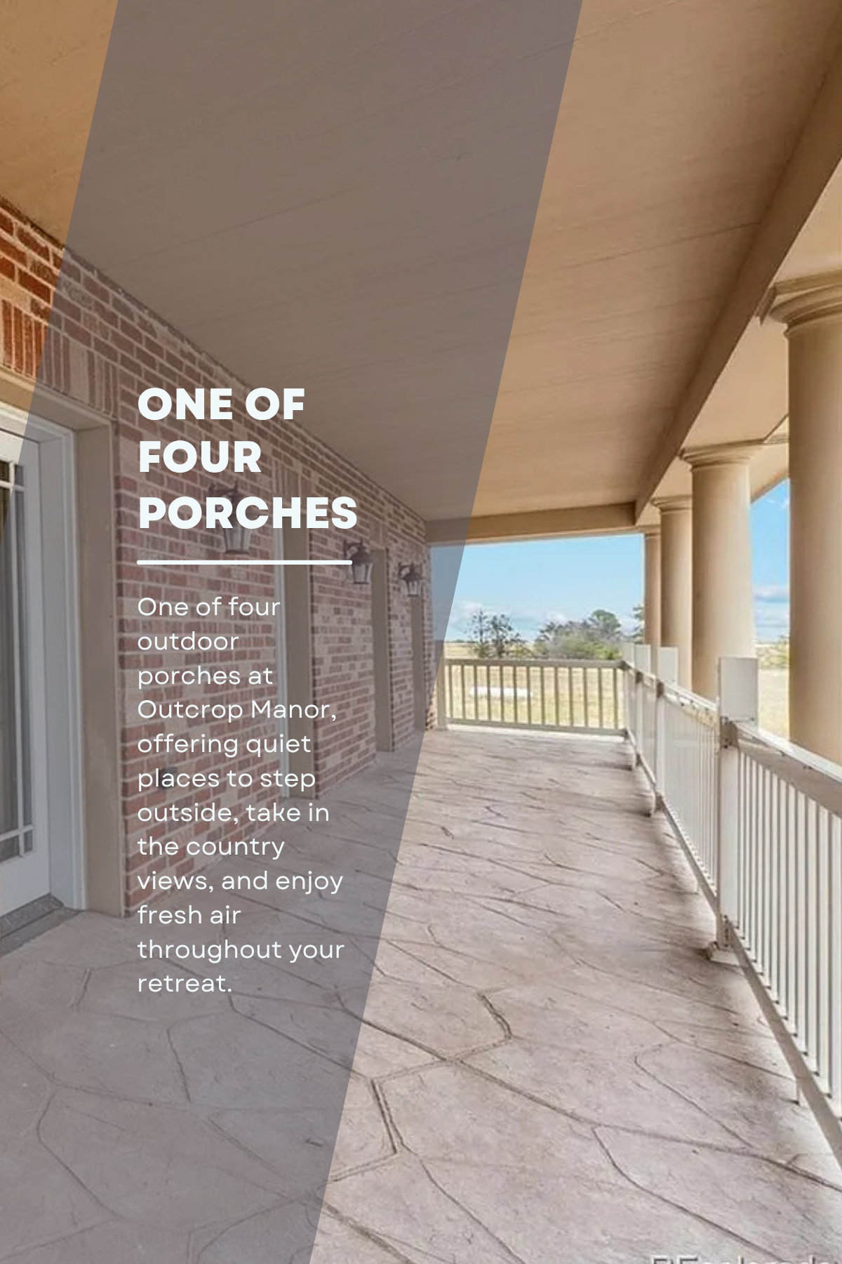A spacious outdoor porch with brick and siding walls, large white columns, stone flooring, and a railing overlooking a rural landscape.