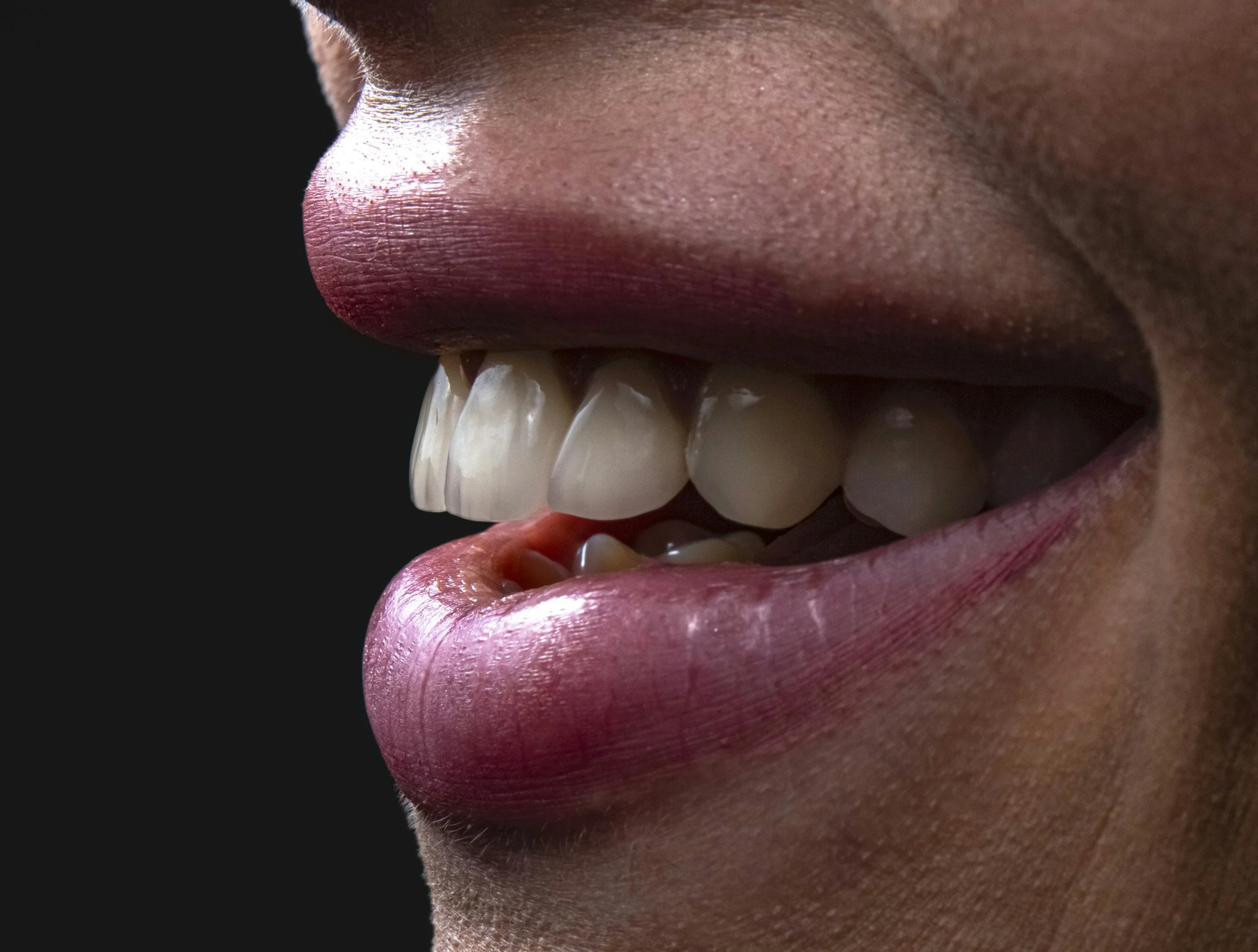 Close-up of a person's mouth with lips slightly parted, revealing teeth and a hint of the tongue.