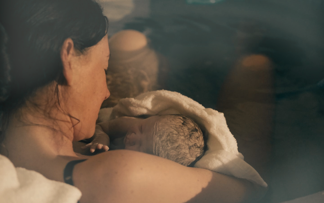 Mother holding a newborn baby after a water birth at home.