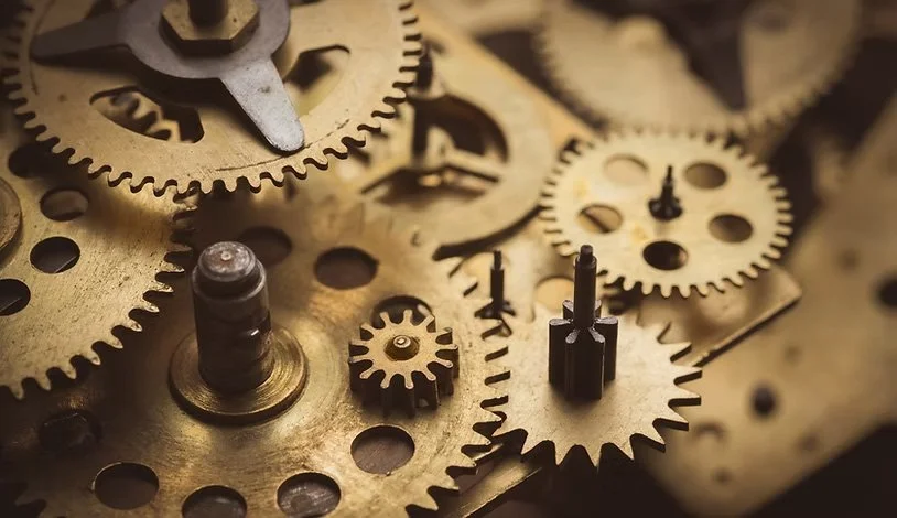 Close-up of various brass and steel gears and cogs inside a mechanical watch movement.