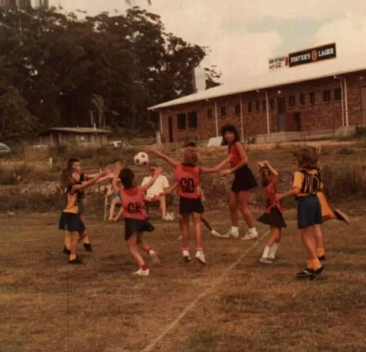 Historic photo of children playing netball outdoors for Mooloolaba Reds