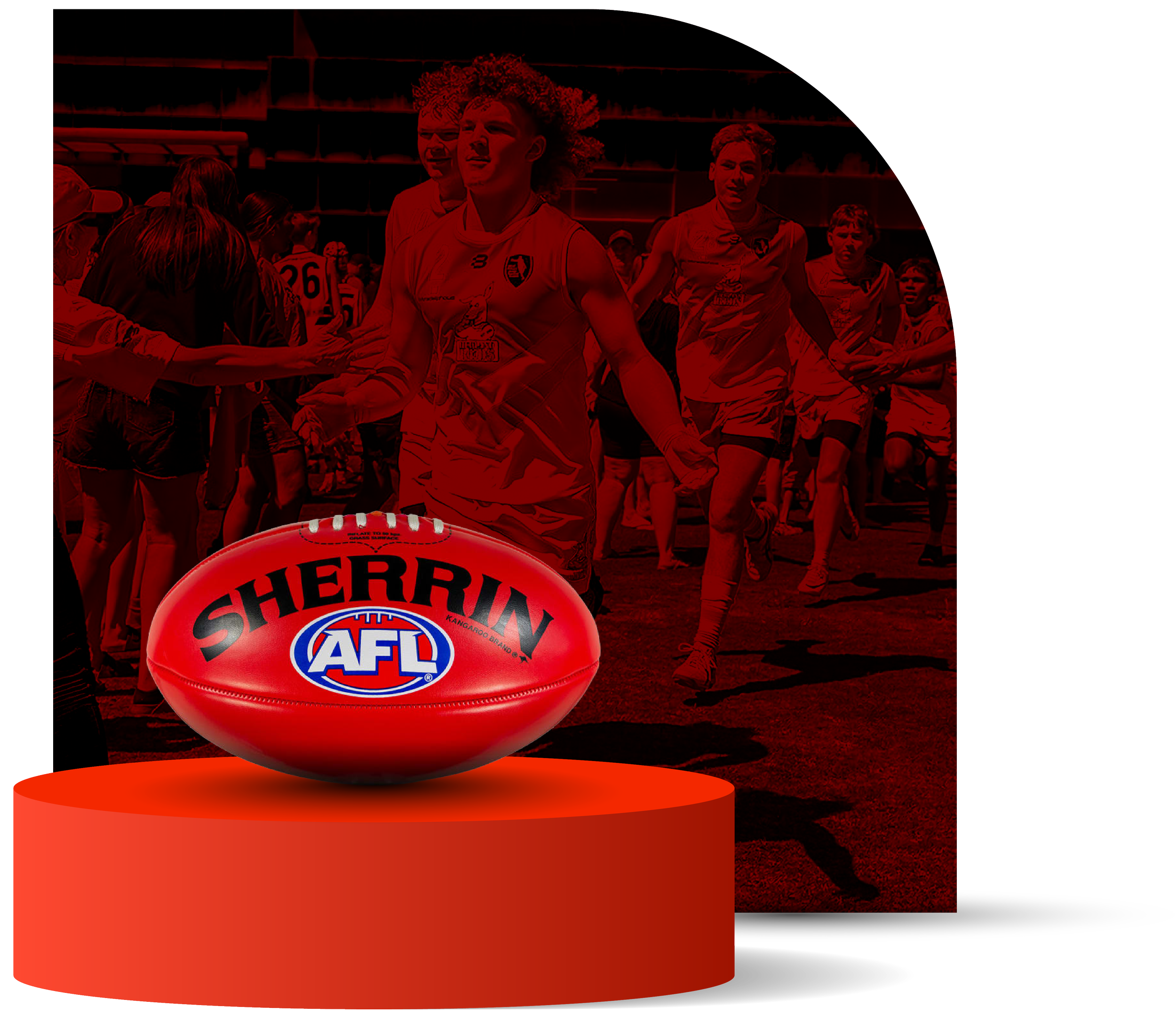 Australian football players walking onto the field with a red AFL football in the foreground resting on a red podium.