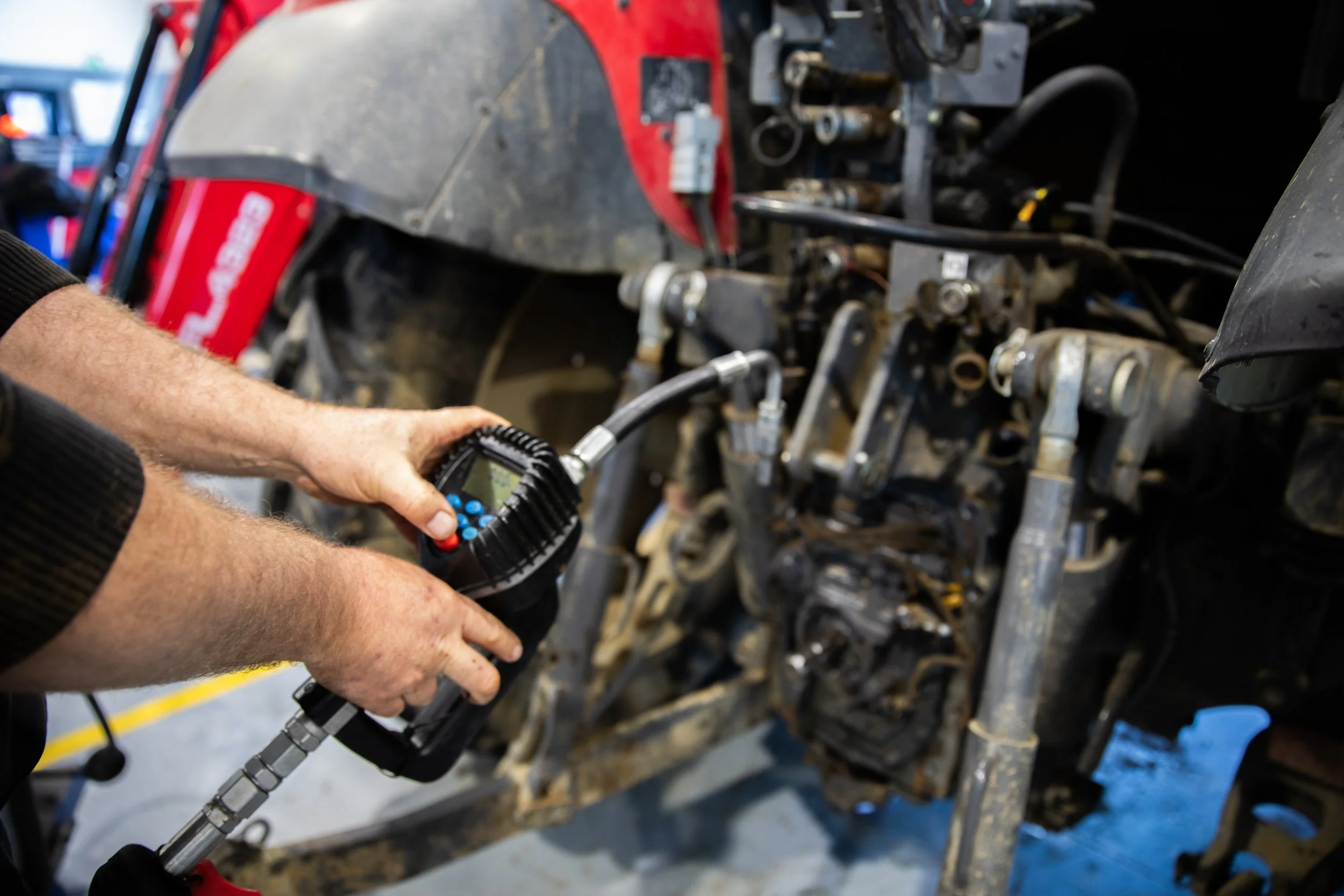 A person using a diagnostic tool on a engine in a workshop.