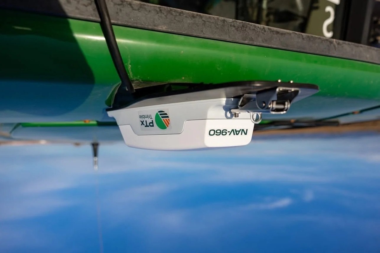 Close-up of a green boat with a white NV-Y960 GPS device attached on the side, with a clear blue sky in the background.