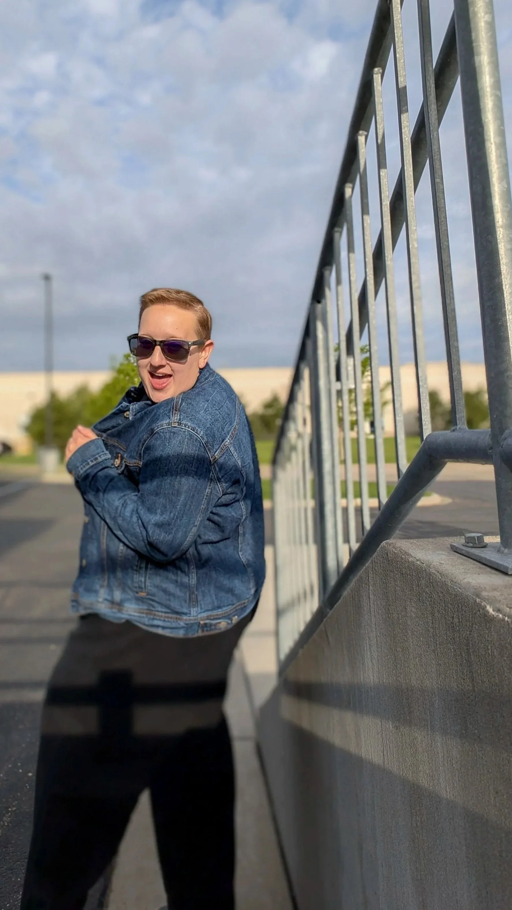 Chaptered Goods founder and maker smiling outdoors in a denim jacket and sunglasses.