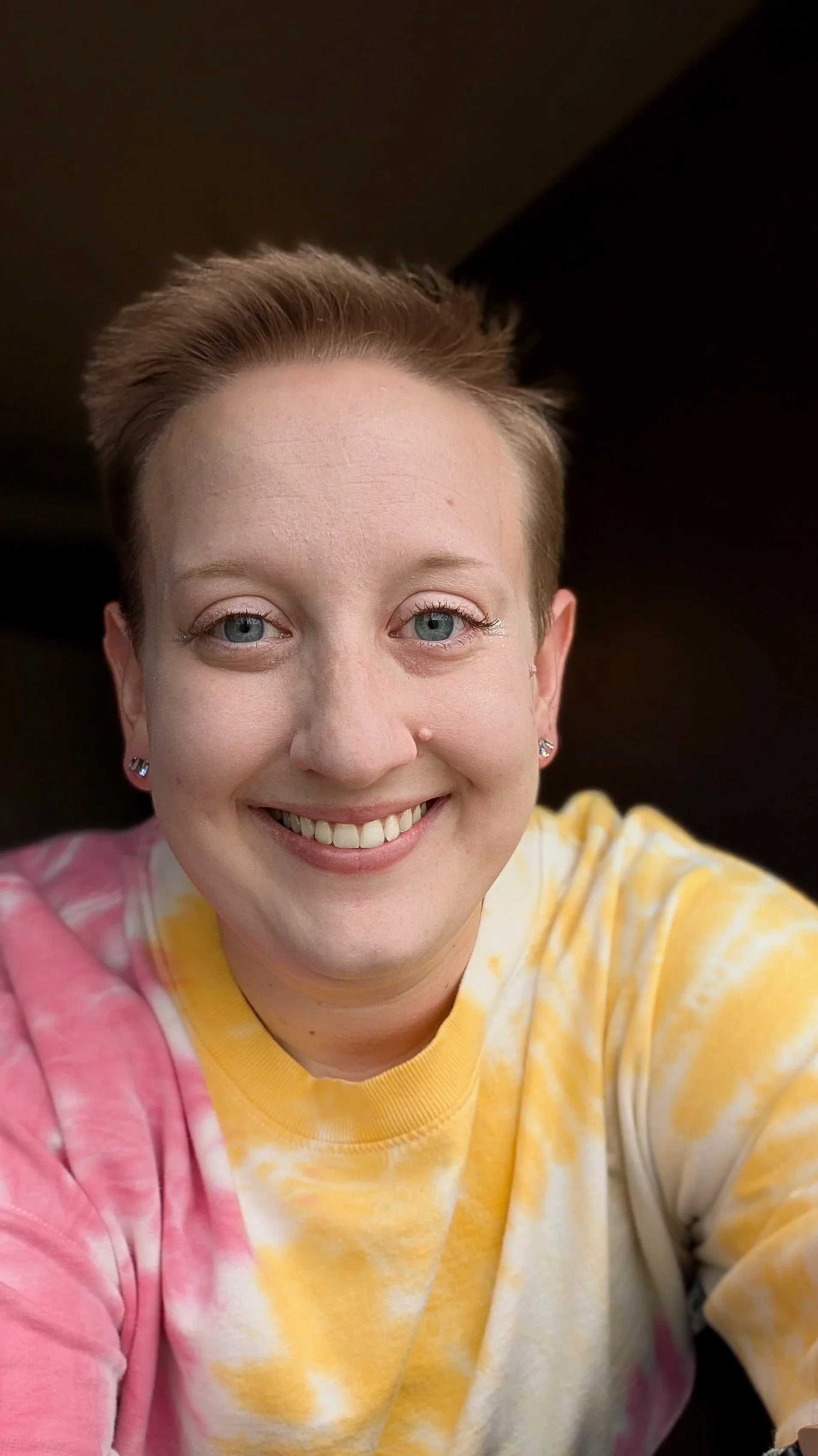 Chaptered Goods founder and maker smiling in a pink and yellow tie-dye sweatshirt.