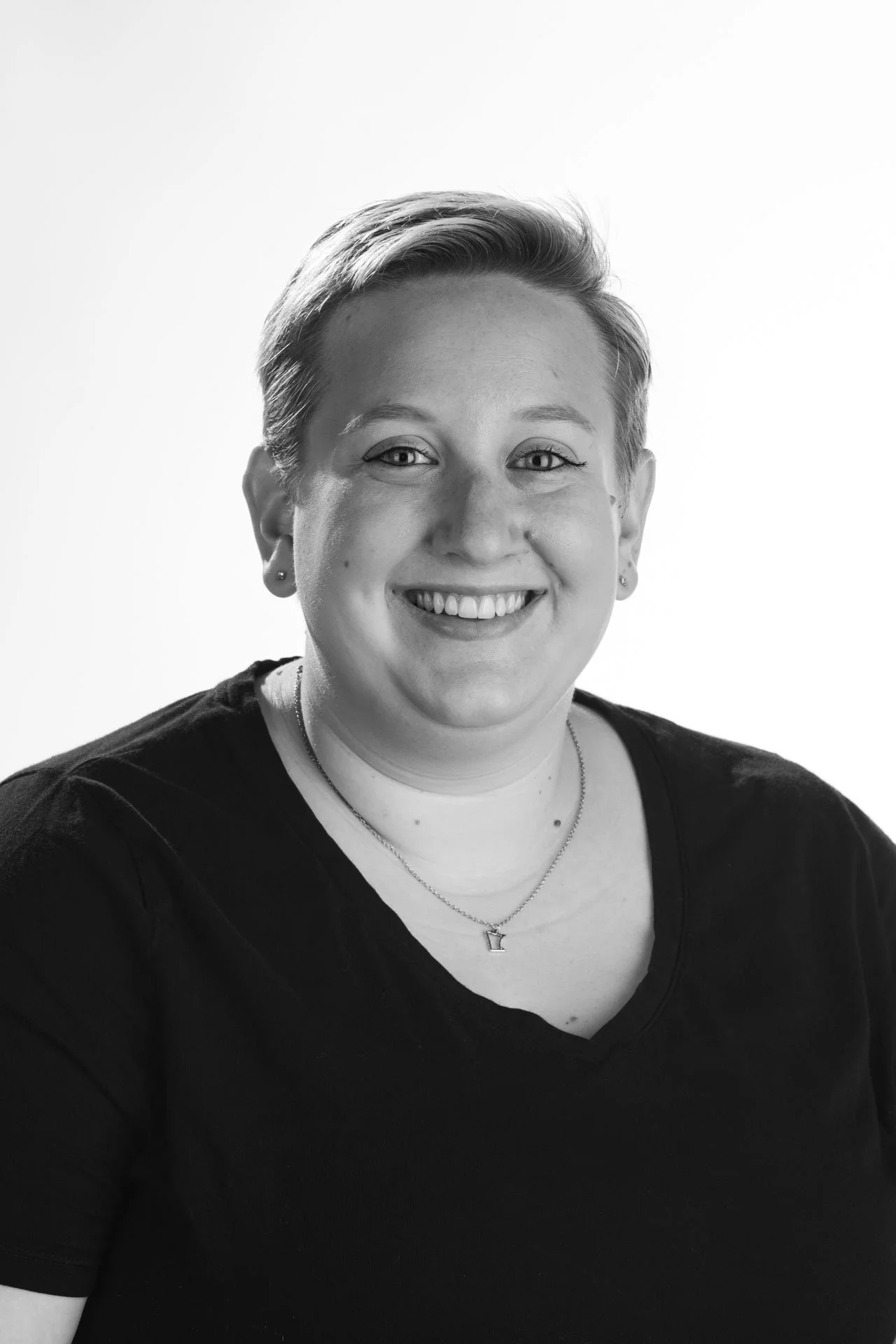 Black and white headshot of a smiling person with short hair against a light background