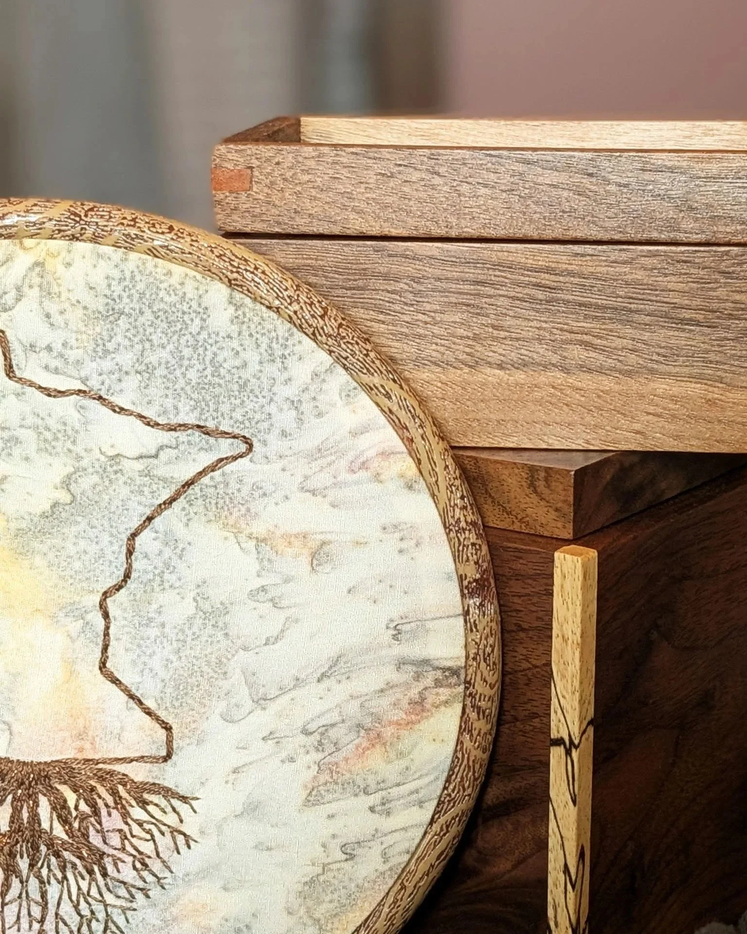 Handcrafted wooden boxes paired with embroidered textile artwork on a neutral studio backdrop