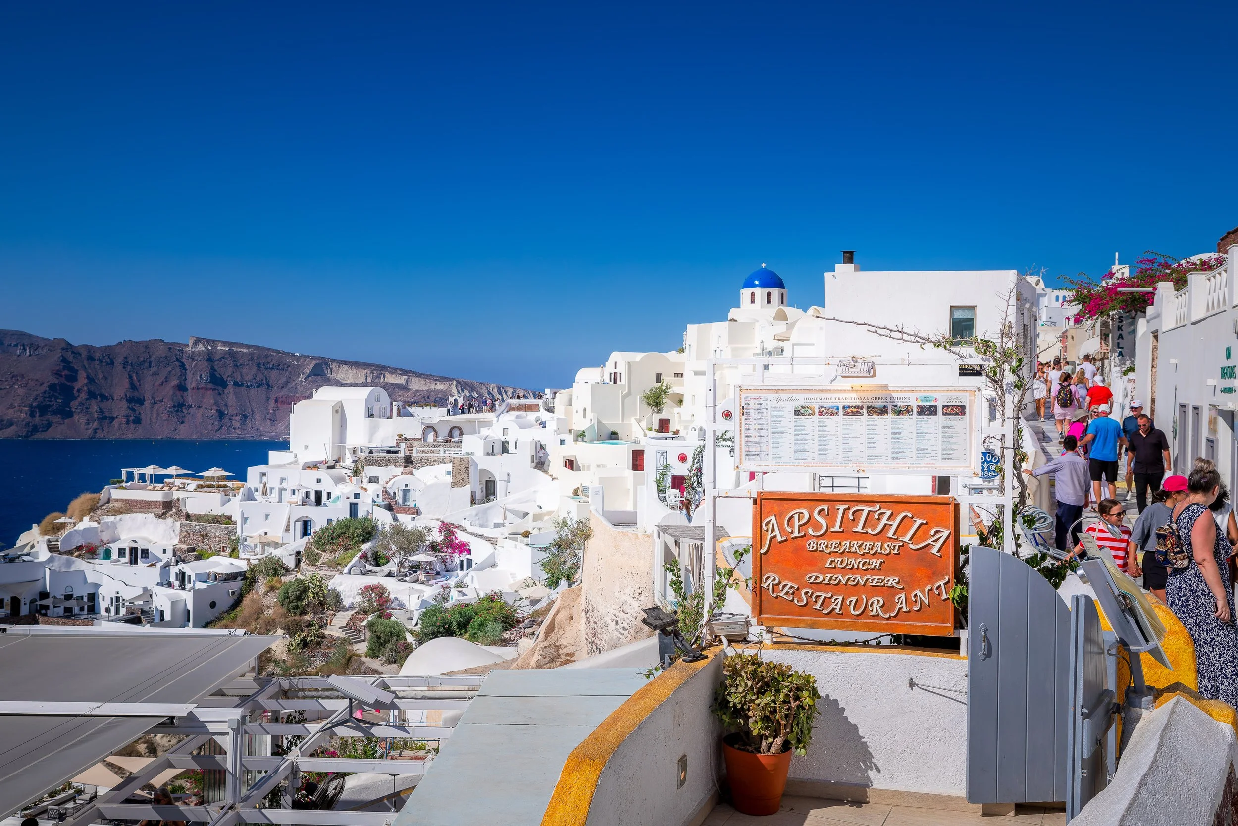 Tourists walking past restaurants in Oia, Santorini, Greece
