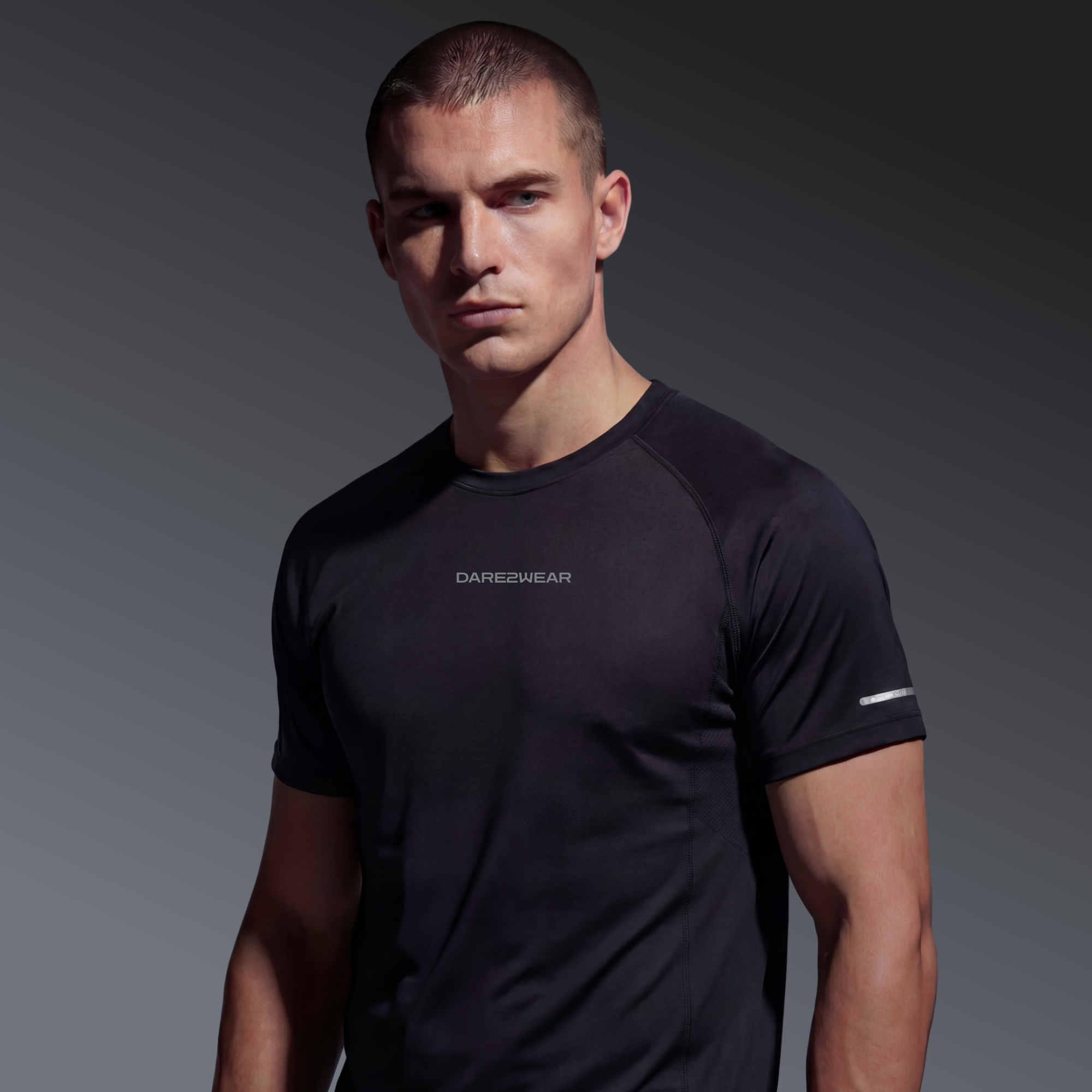 A young man with short blonde hair and a serious expression, wearing a black athletic t-shirt against a dark gray background.
