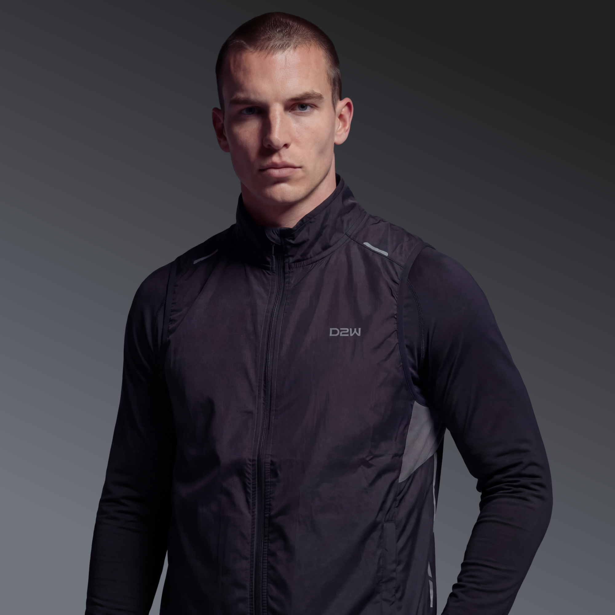 A young man with short hair wearing a black D2W sports jacket against a gray background.