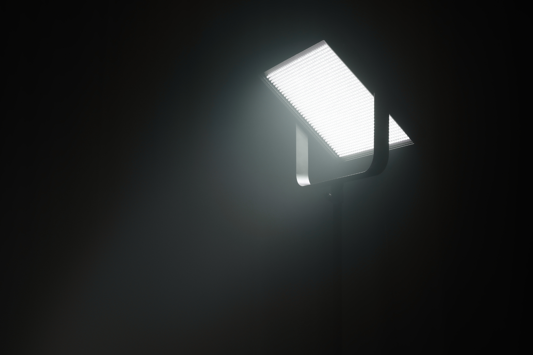 Bright LED light panel mounted on ceiling against a dark background.