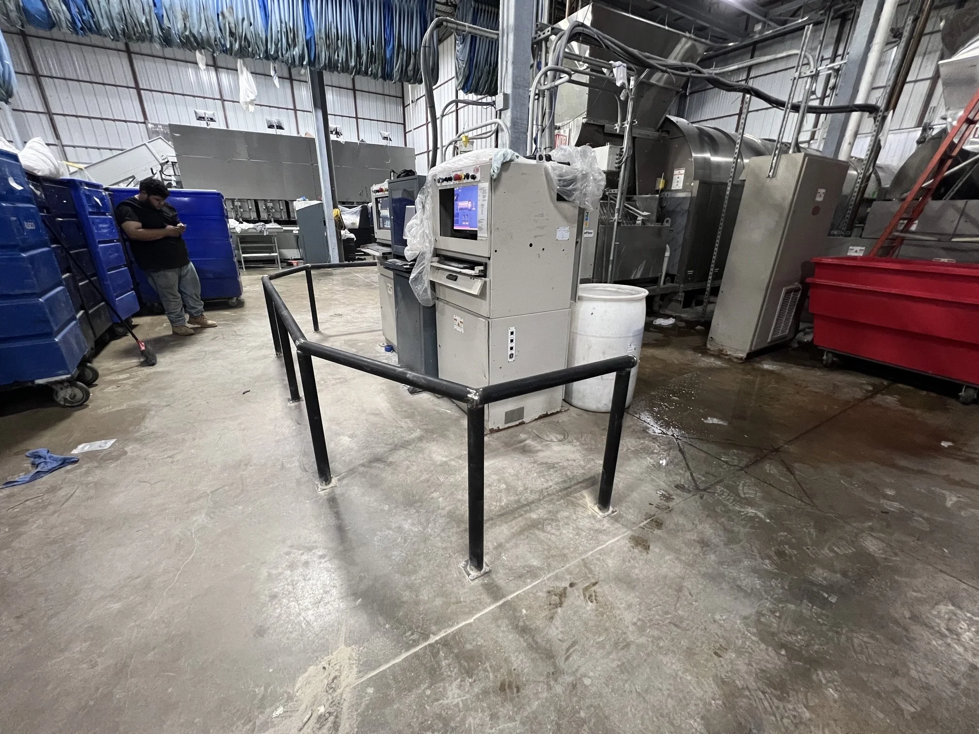 Custom industrial guardrail installed in a commercial dry cleaning facility to protect computer systems from impact by rolling carts. Heavy-duty steel safety barrier designed to prevent damage to sensitive equipment while maintaining workflow efficie