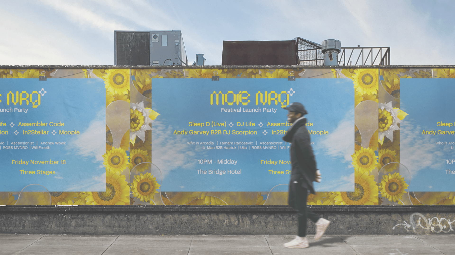 A person walking past a large colorful billboard advertising the More NRG music festival launch party, with yellow sunflower graphics and blue background, on a city sidewalk.