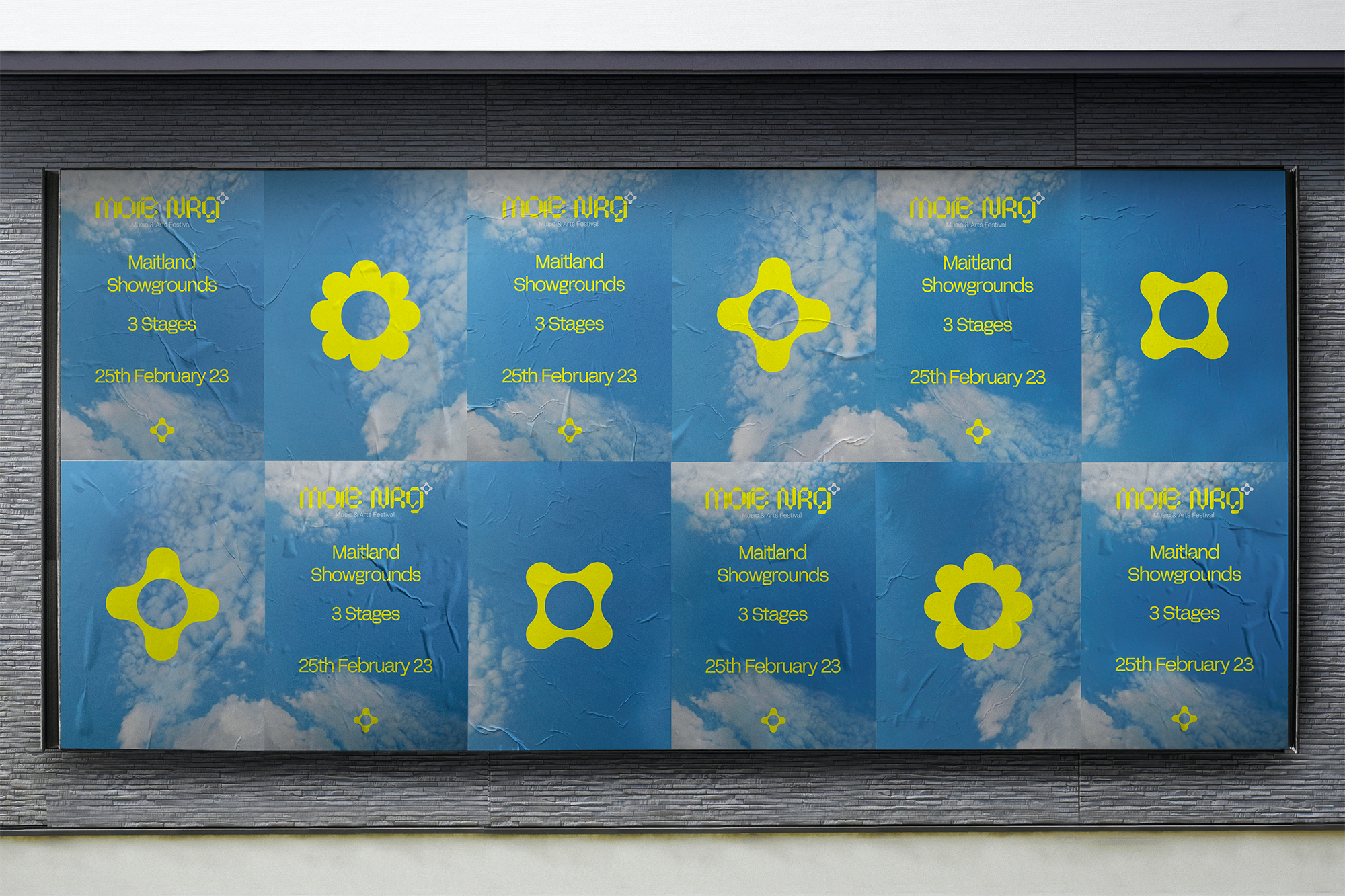 Large outdoor billboard with blue sky and clouds background, featuring yellow and gray shapes and text promoting 'Mote NRG' art festival at Maitland Showgrounds on February 25th, with details about 3 stages.