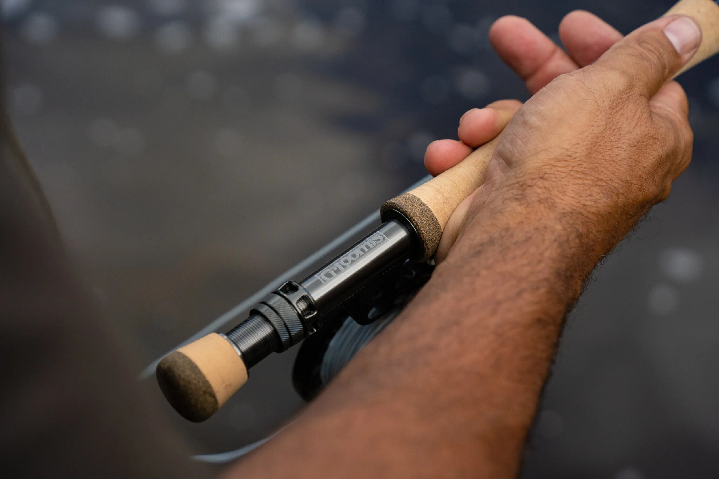 A person holding a fishing rod with both hands against a blurred background.