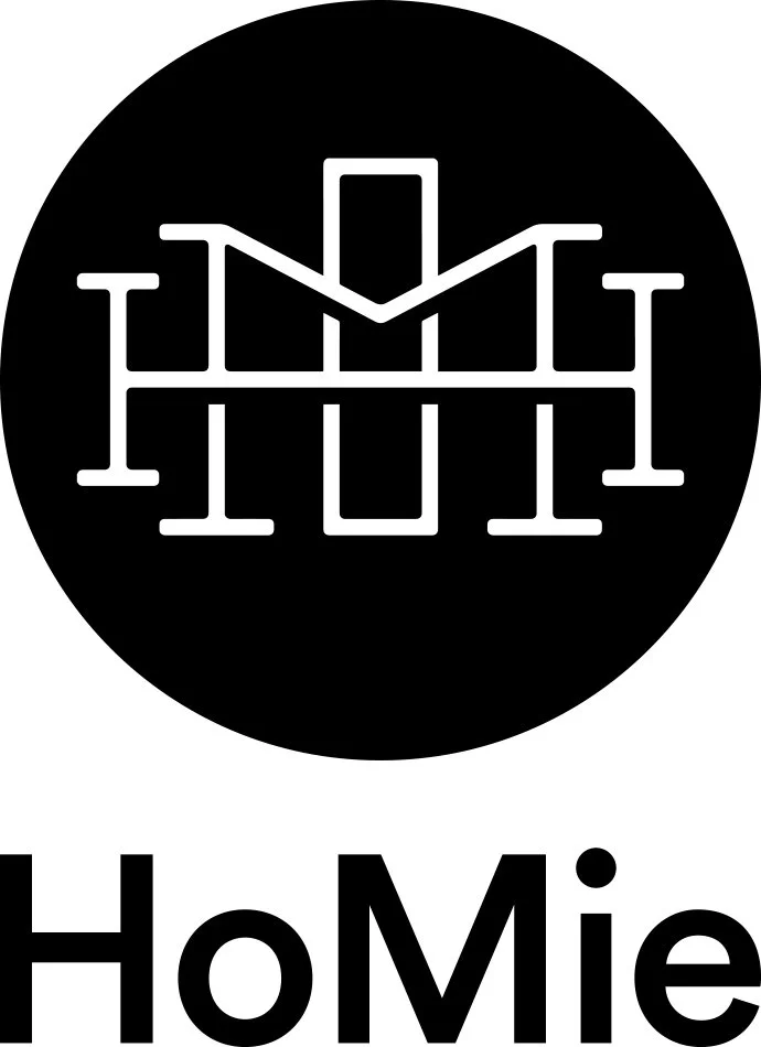Logo with a white line drawing of a house in a black circle, with the word 'HoMie' in bold black letters below.