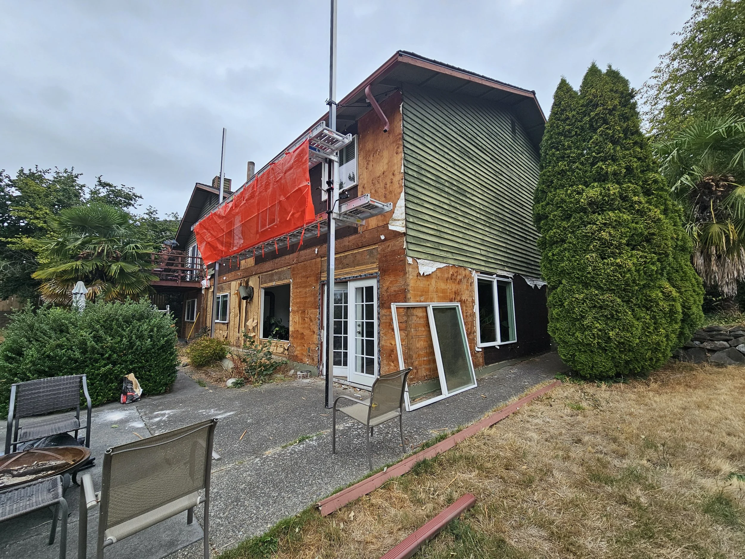 Back of a house under renovation for new siding with partially exposed wooden exterior.
