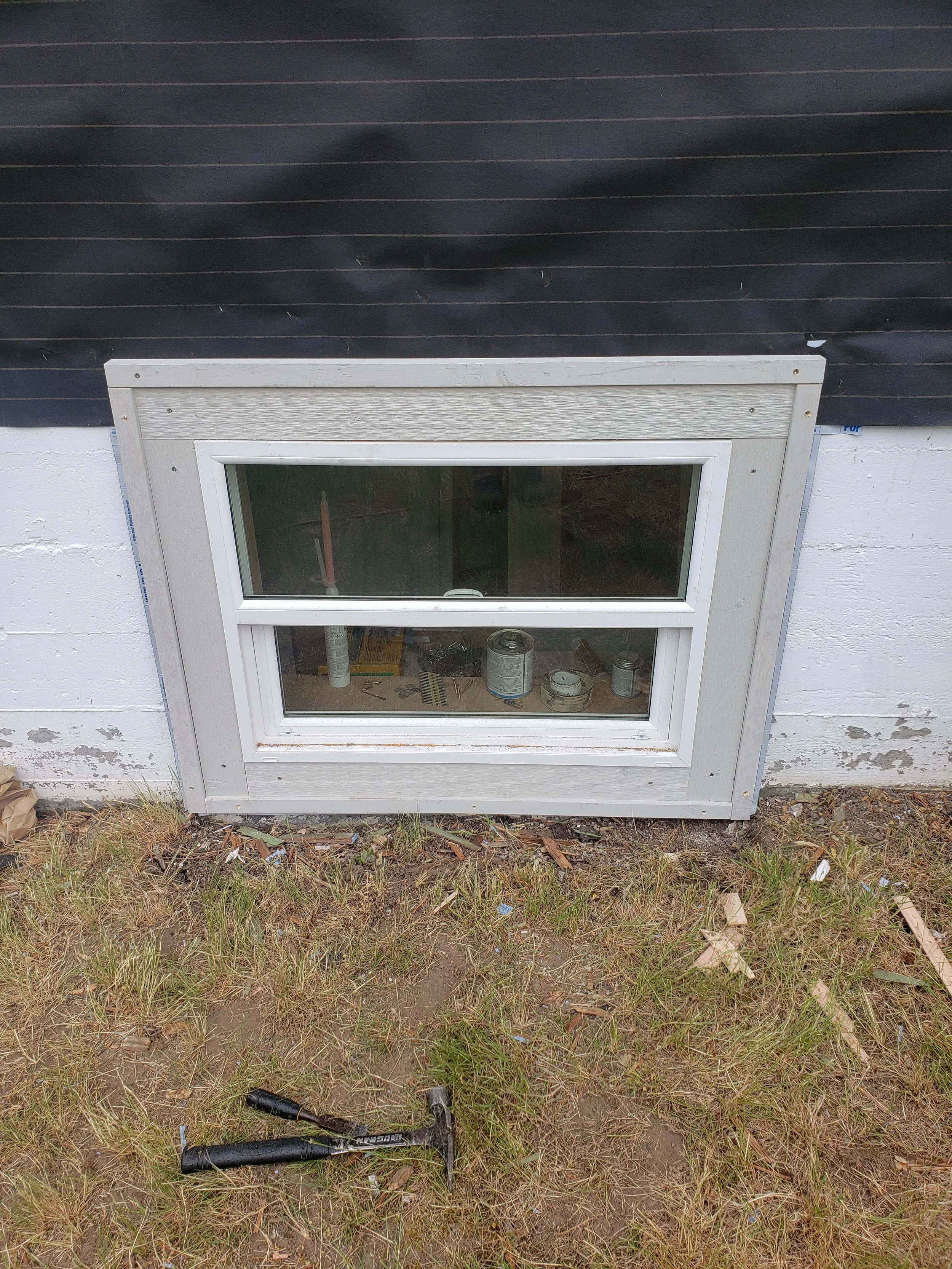 A newly installed daylight basement window with white trim.