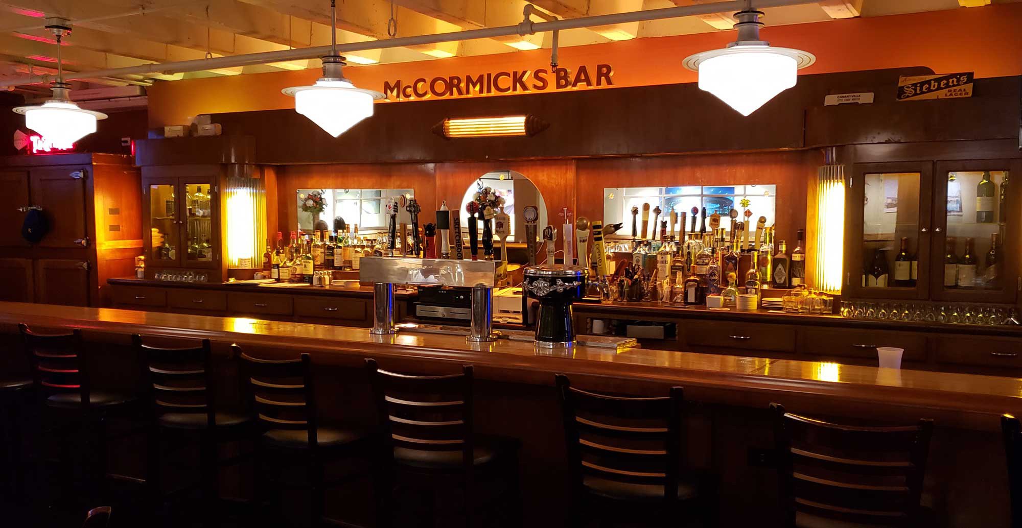 Inside the largest bar in Evanston at Prairie Moon. Bar is made from recycled bowling floor. 17 tap handles with the best local beers in Chicago. The bar has warm lighting, a large mirror behind the counter, and seating arranged along the front.