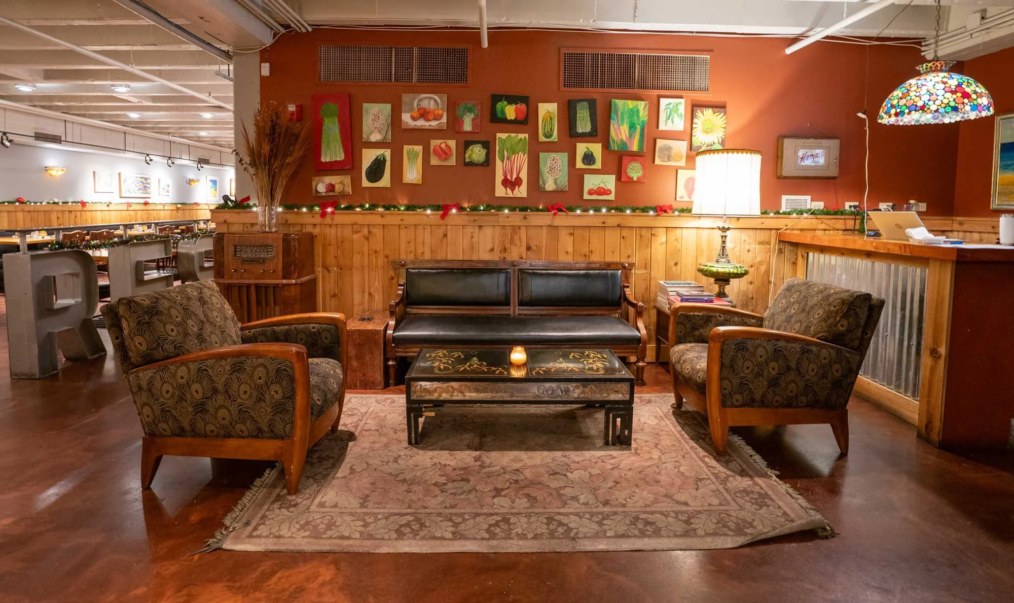 Cozy lounge area inside Evanston Restaurant Prairie Moon with two patterned armchairs, a leather sofa, a decorative coffee table.