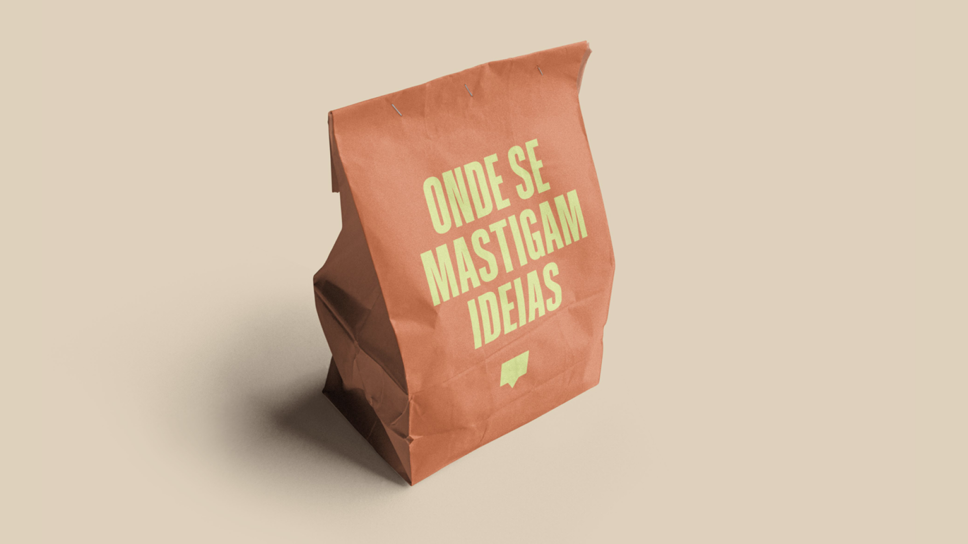 Sanduíche de papel marrom com a frase "Onde se mastigam ideias" escrito em letras amarelas na frente