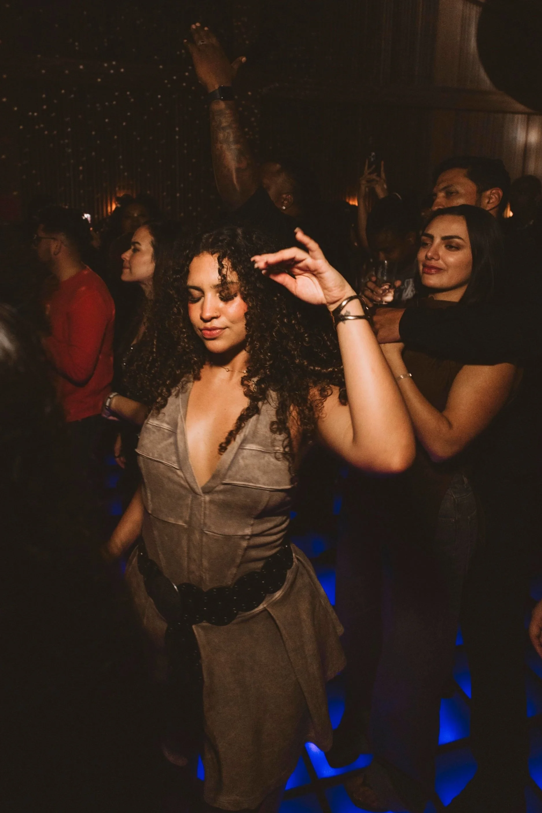 People dancing and enjoying music at Casa de Afro by Dr. ADO in Mexico City. Mimi Disco is a lively nightclub, the floor is illuminated by blue and orange lighting.