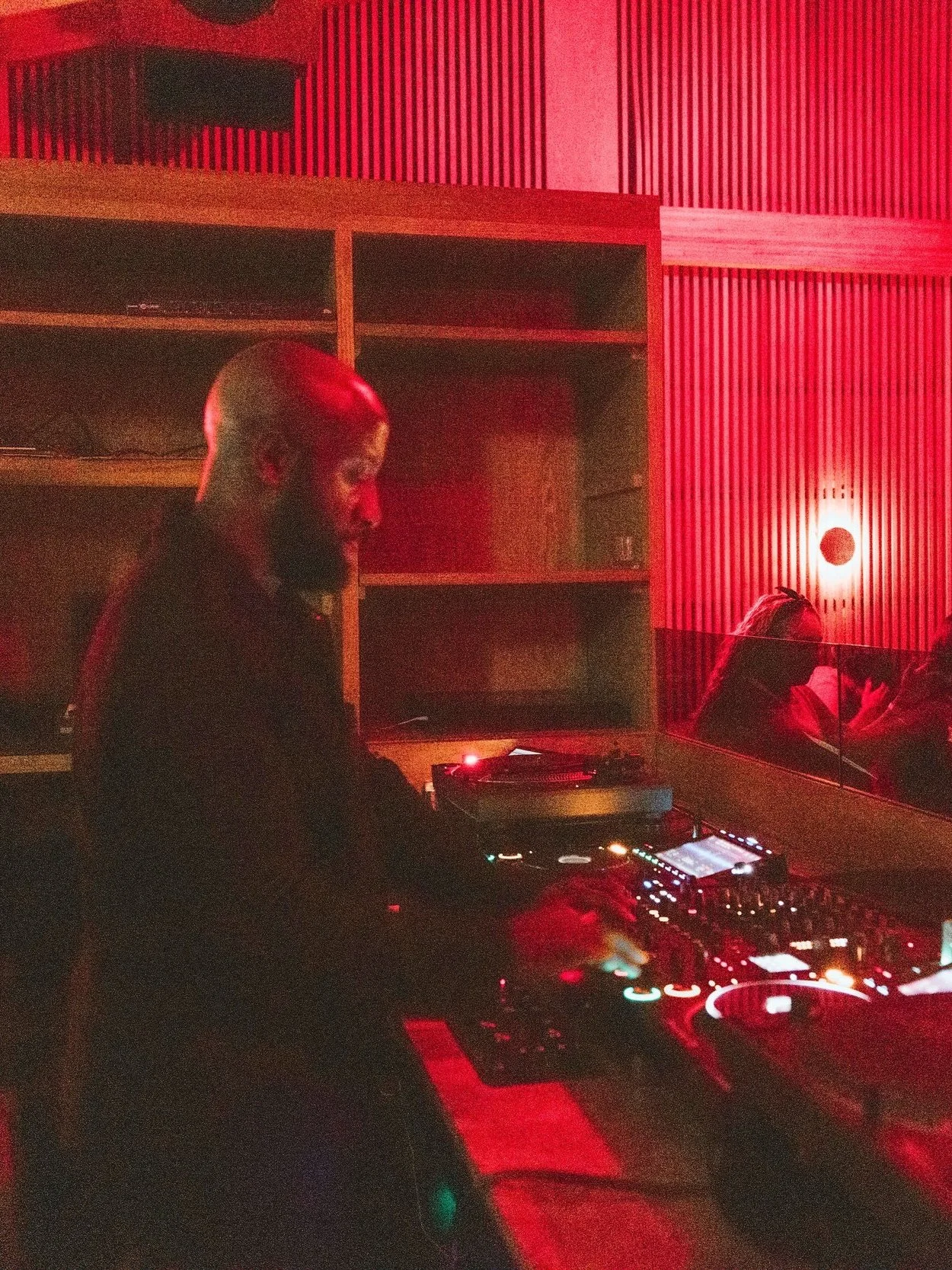 Dr. ADO DJing at Mimi Disco is Mexico City for Casa de Afro with red lighting and wooden wall background.