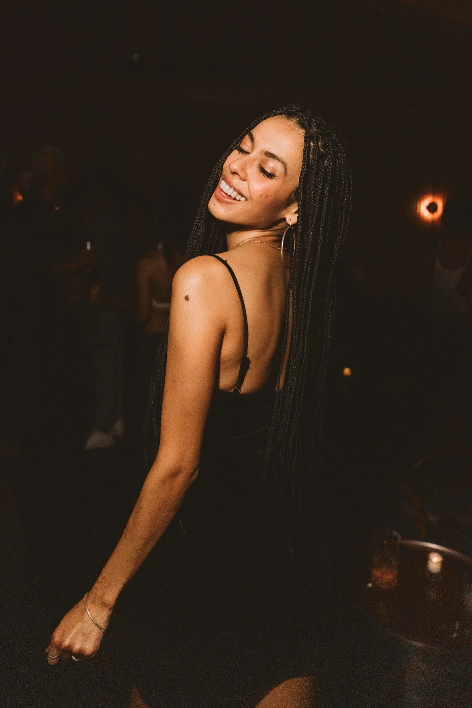 A woman with long braided hair smiling and dancing at Casa de Afro by Dr. ADO in Mexico City. 