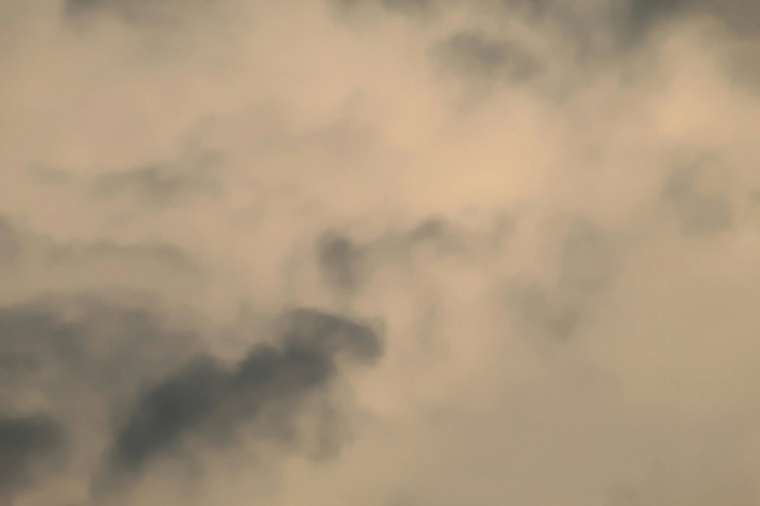 Blurred sky with dark clouds and patches of light, possibly during sunset or sunrise.