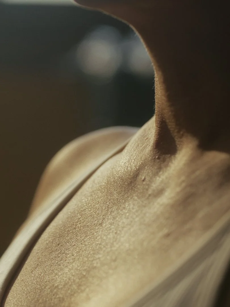 Close-up of a beige or tan leather surface with light reflecting off its textured surface.