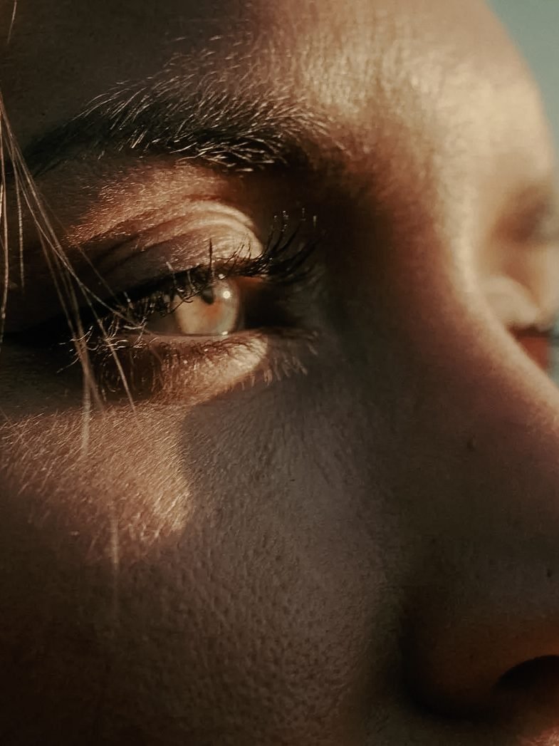 Close-up of a person's eye and nose, with sunlight illuminating the face.